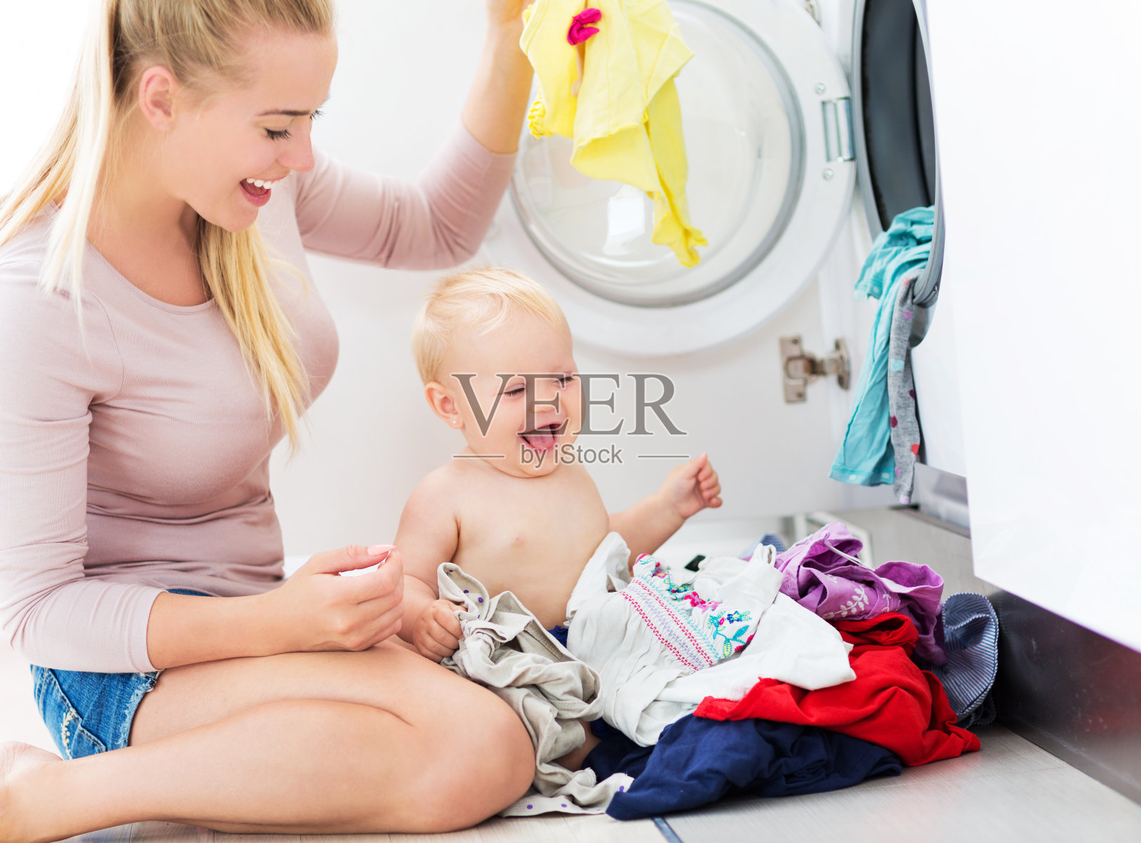母亲和婴儿把衣服装进洗衣机照片摄影图片