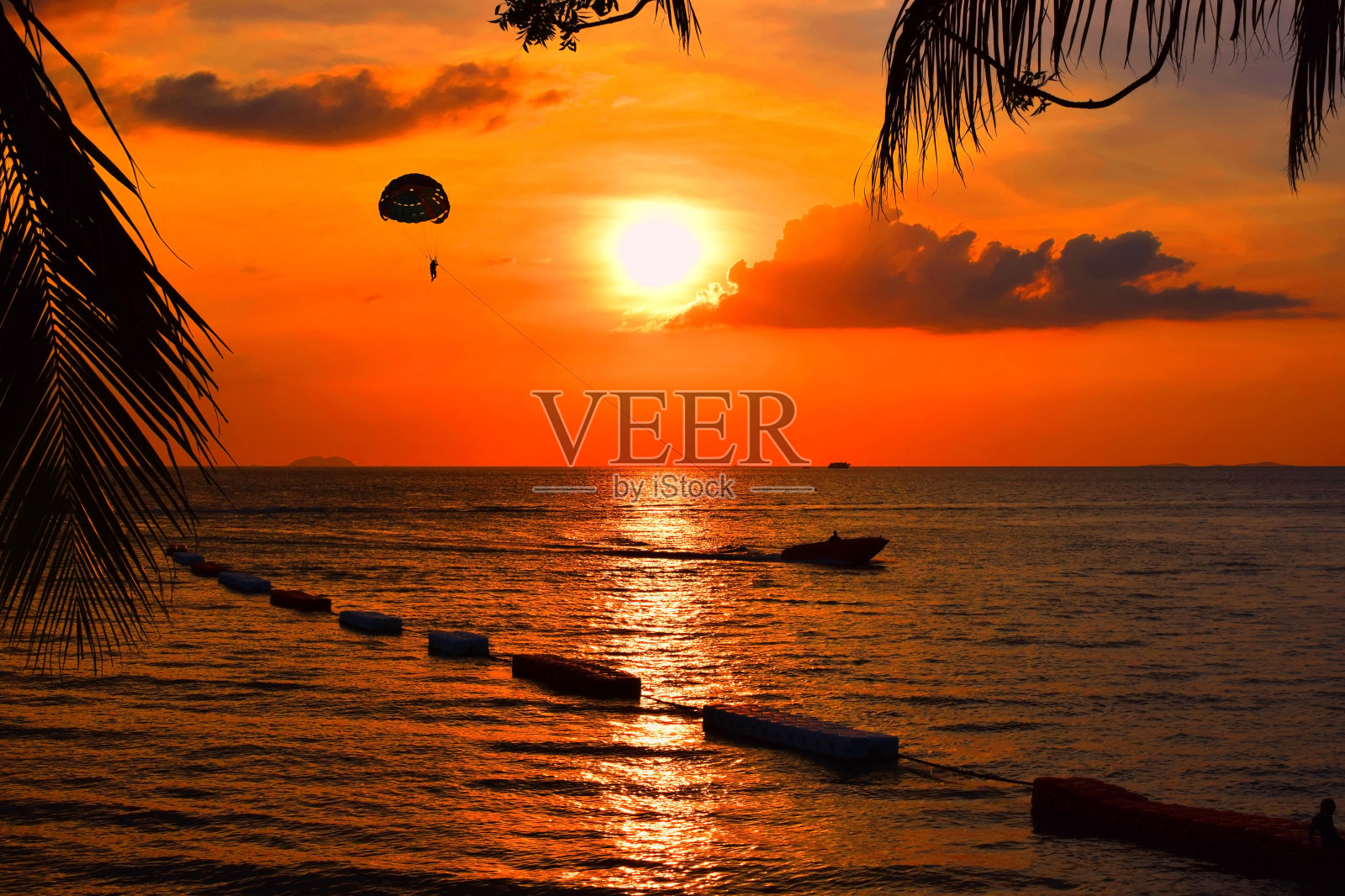 日落时在海边玩降落伞和划船照片摄影图片