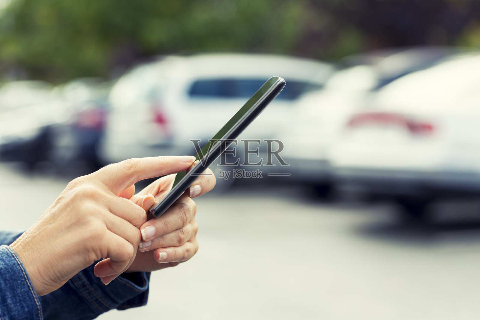 一个女人用她的手机应用程序连接她的车。照片摄影图片