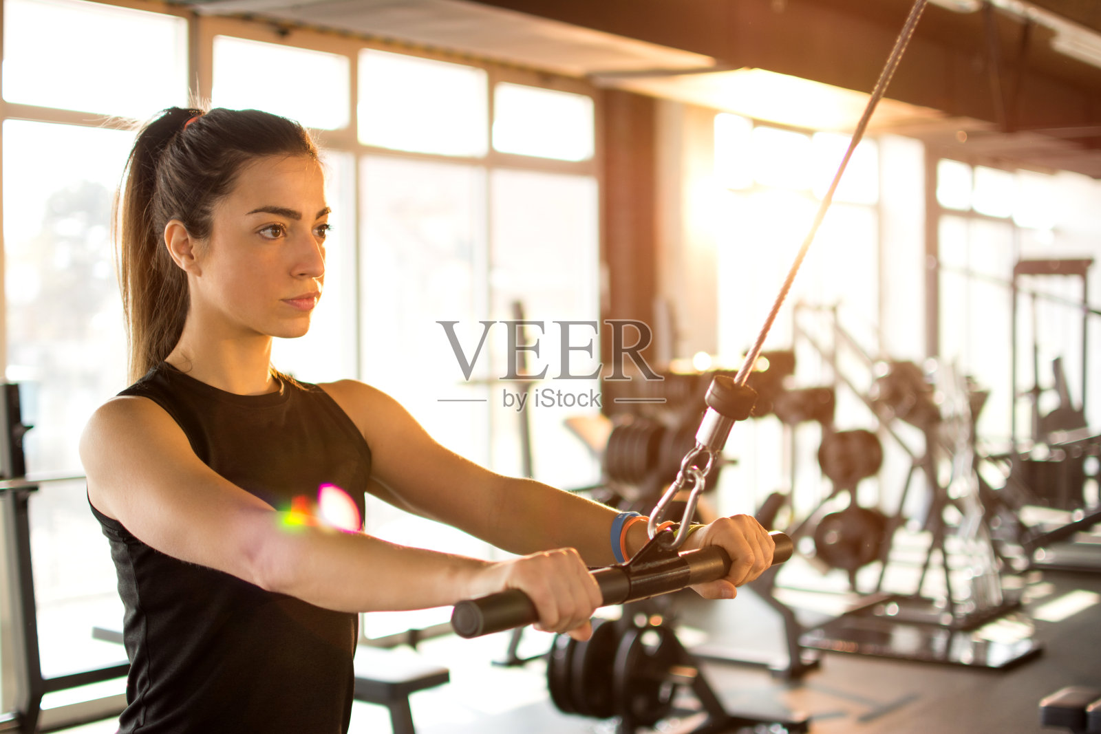 年轻的健身女士在健身房用健身器材进行锻炼。照片摄影图片