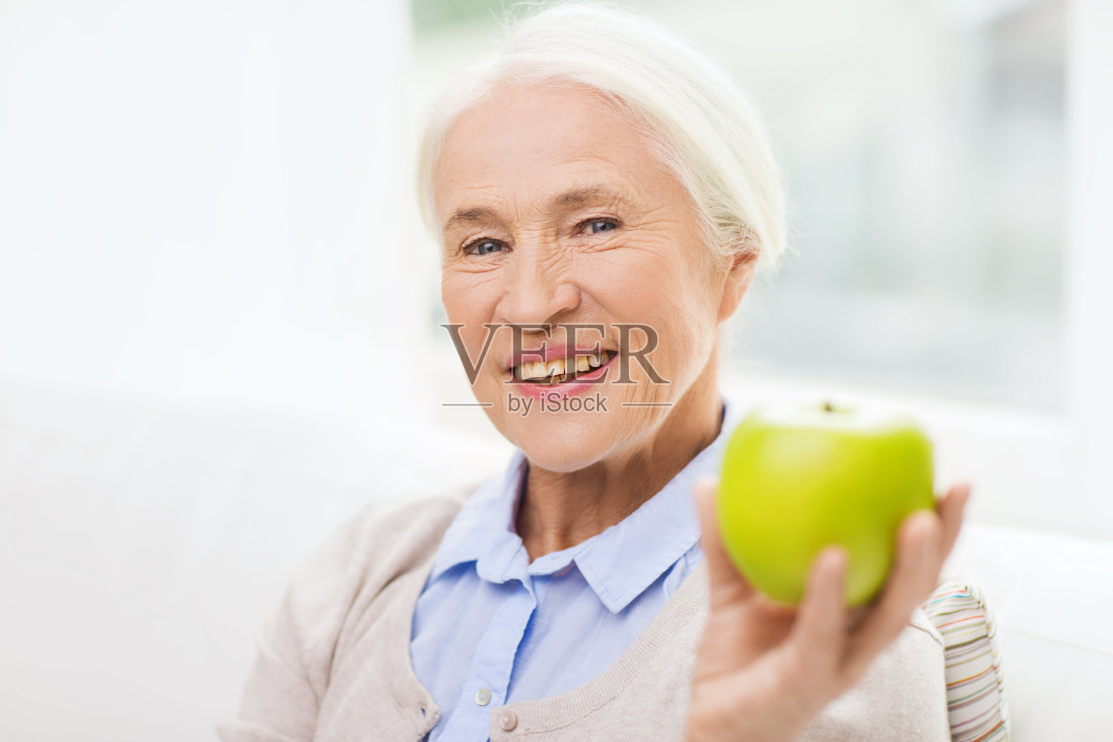 快乐的老女人带着青苹果在家照片摄影图片