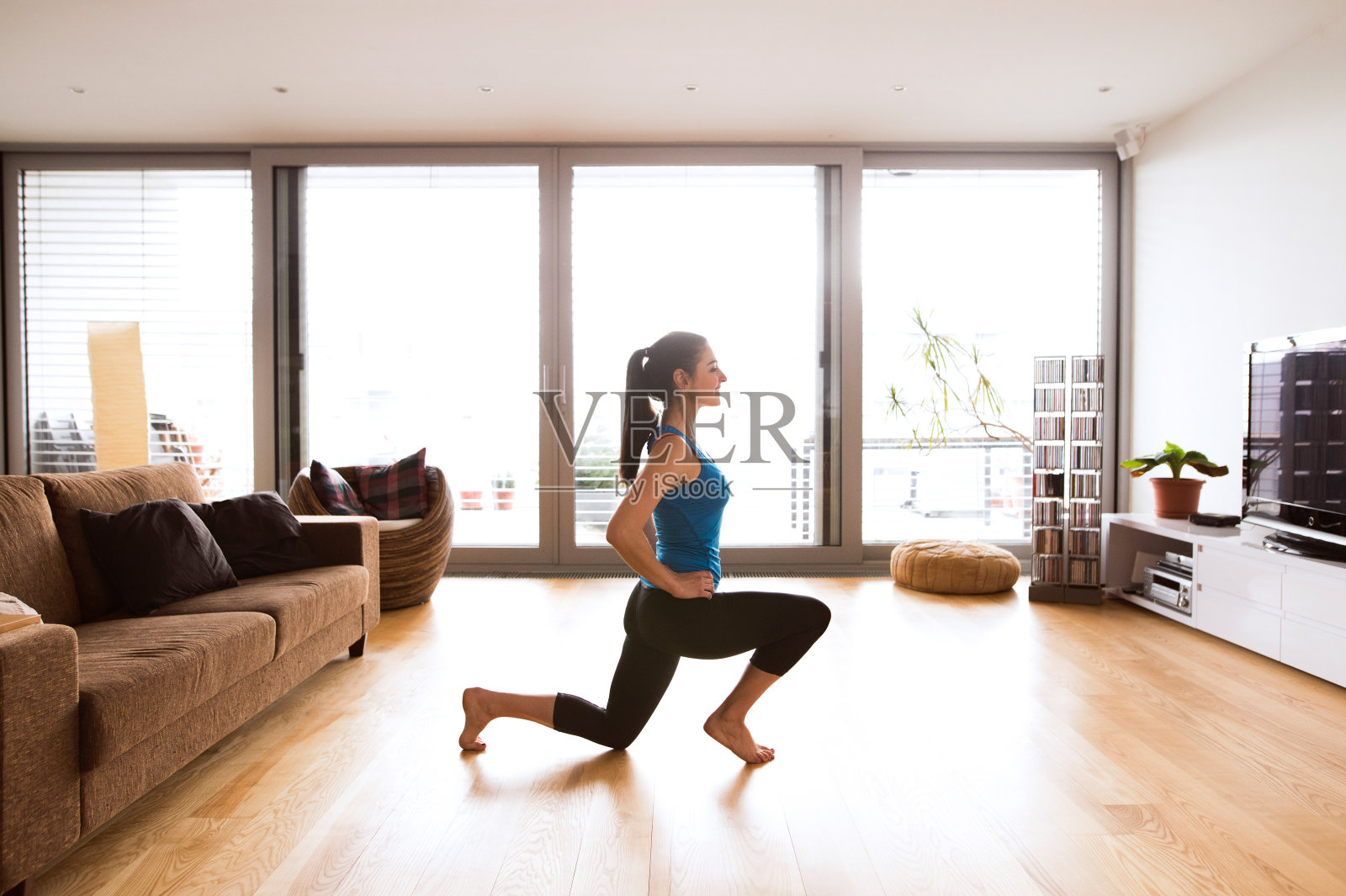 年轻女子在家锻炼，伸展双腿。照片摄影图片