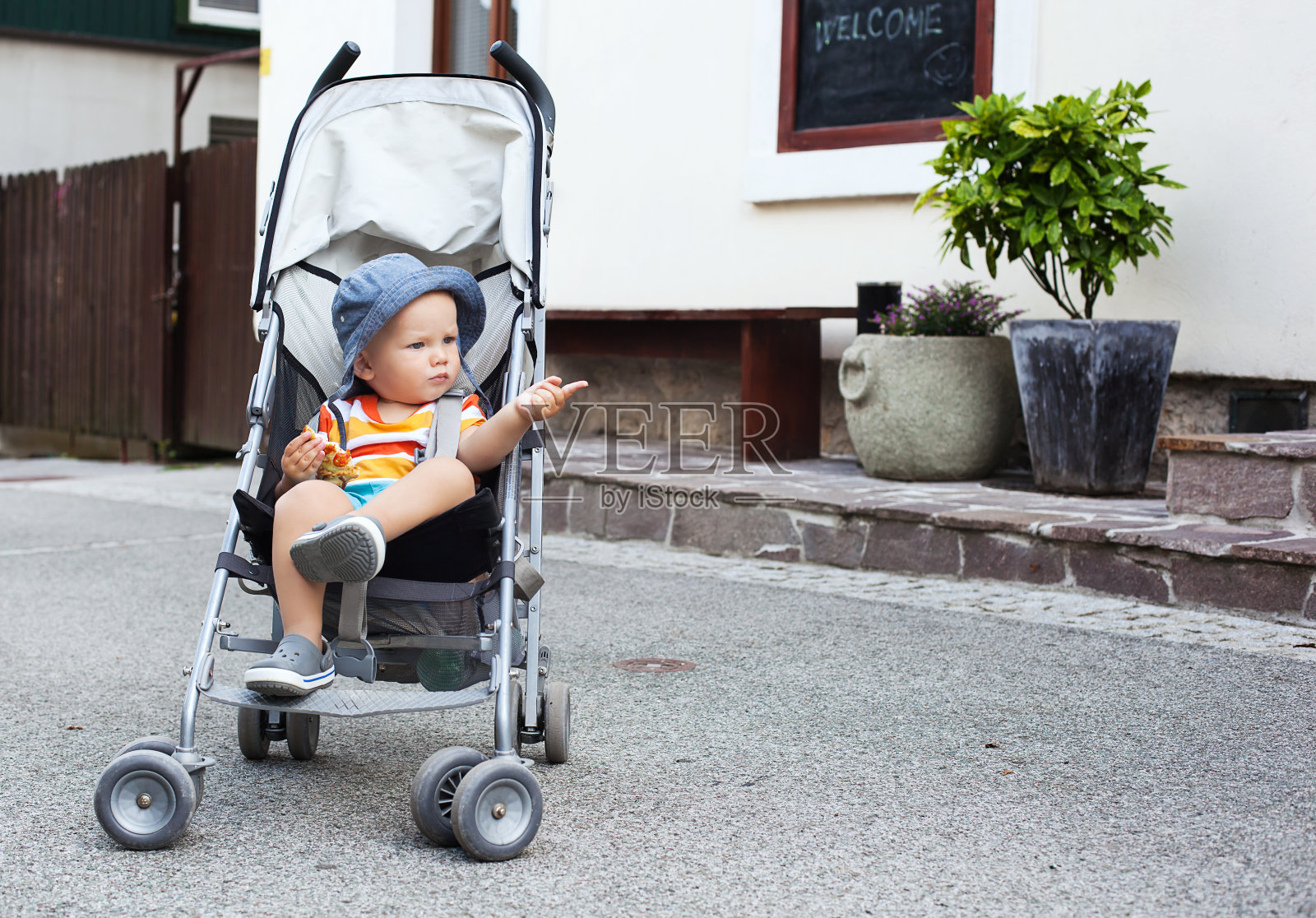 街上可爱的婴儿车里蹒跚学步的孩子。照片摄影图片