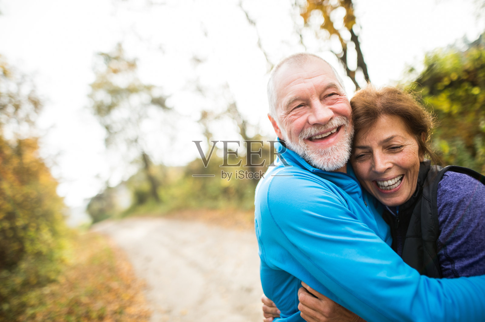一对美丽的老年夫妇在阳光明媚的秋日森林里奔跑照片摄影图片
