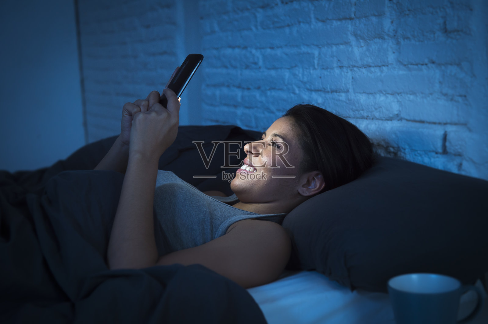 女孩深夜在床上用手机开心放松照片摄影图片