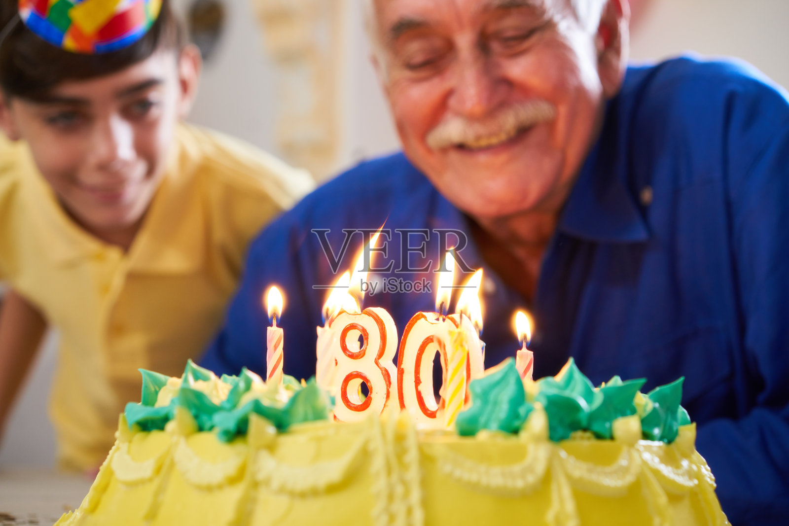 男孩和老人吹蜡烛在蛋糕生日派对照片摄影图片