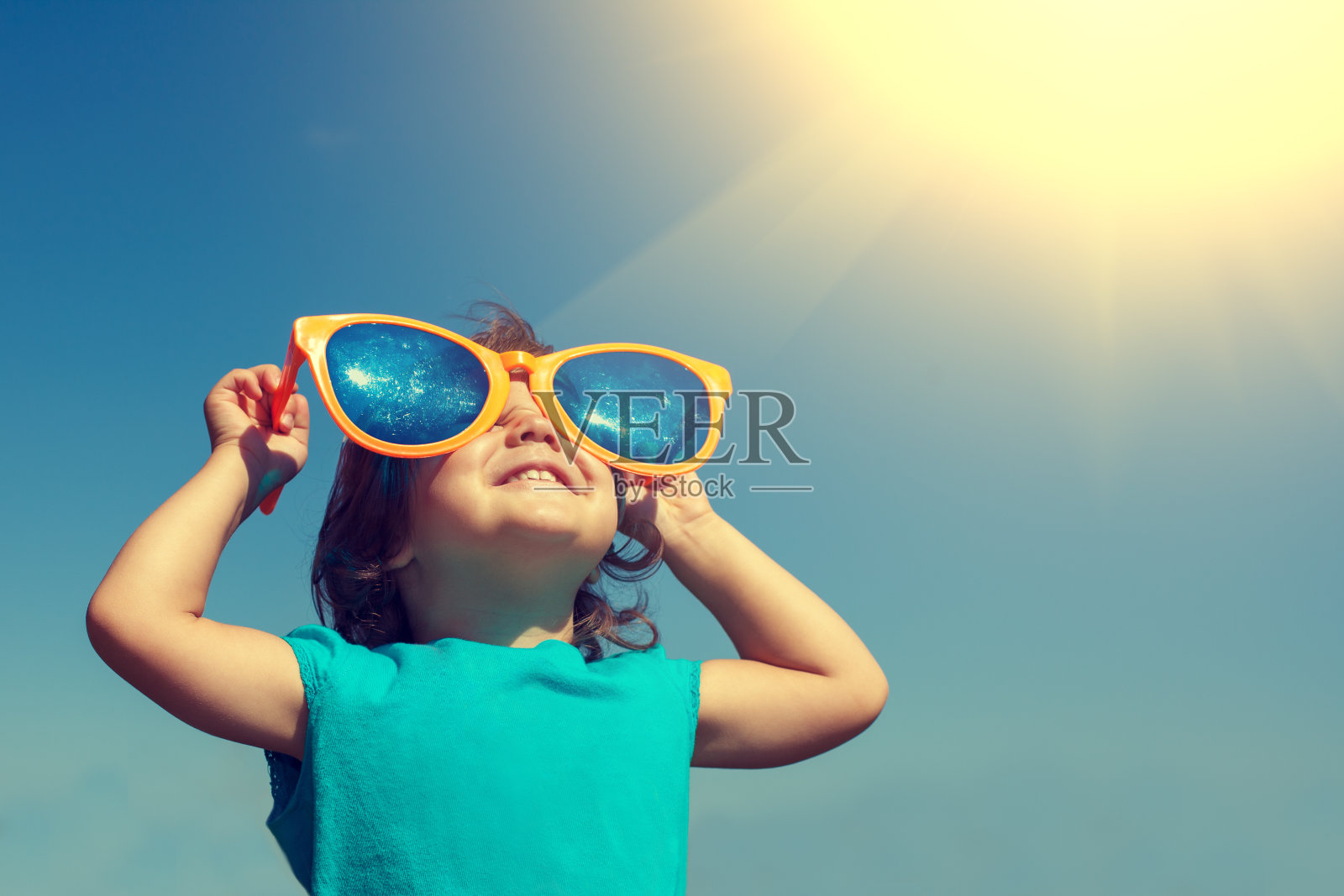 快乐的小女孩戴着大大的太阳镜看着太阳照片摄影图片