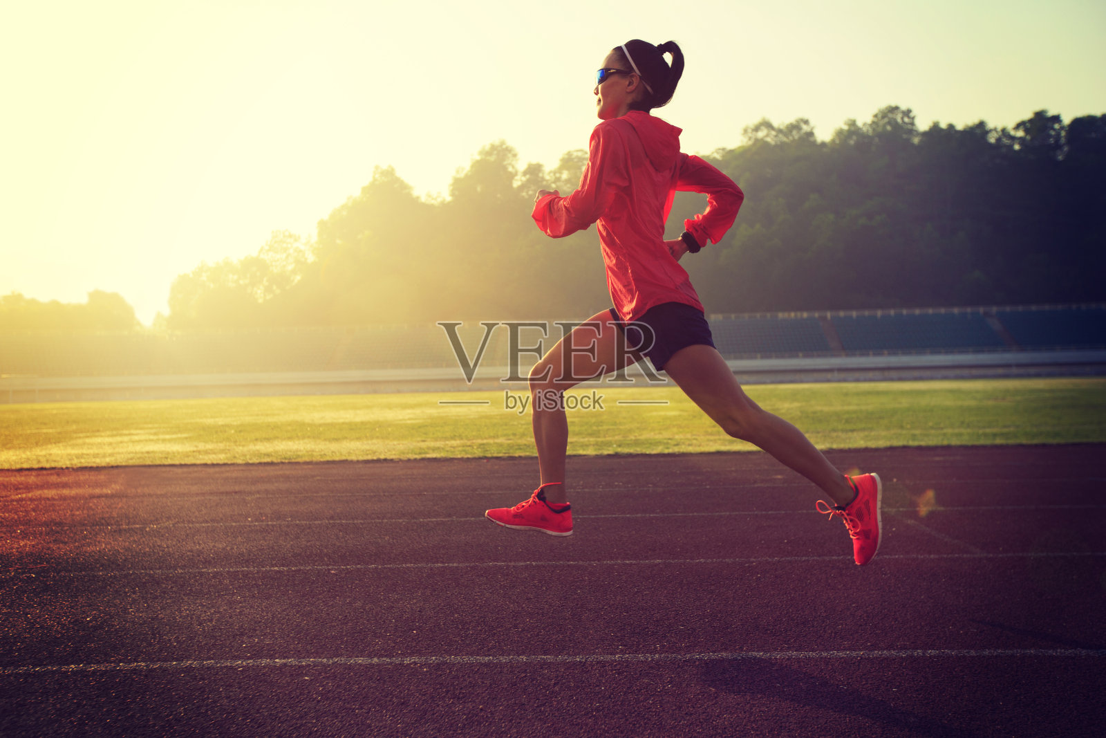 年轻的健身女运动员在体育场跑道上跑步照片摄影图片