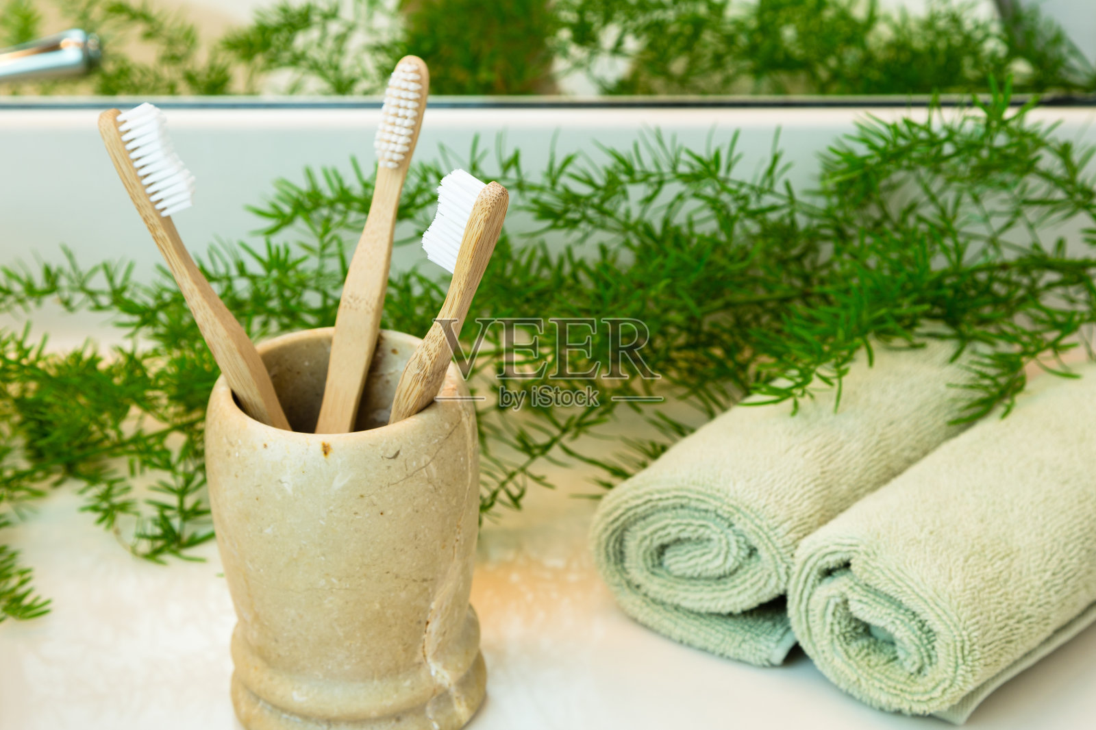 茶杯里的竹子牙刷，浴室台面上的毛巾和蔬菜照片摄影图片
