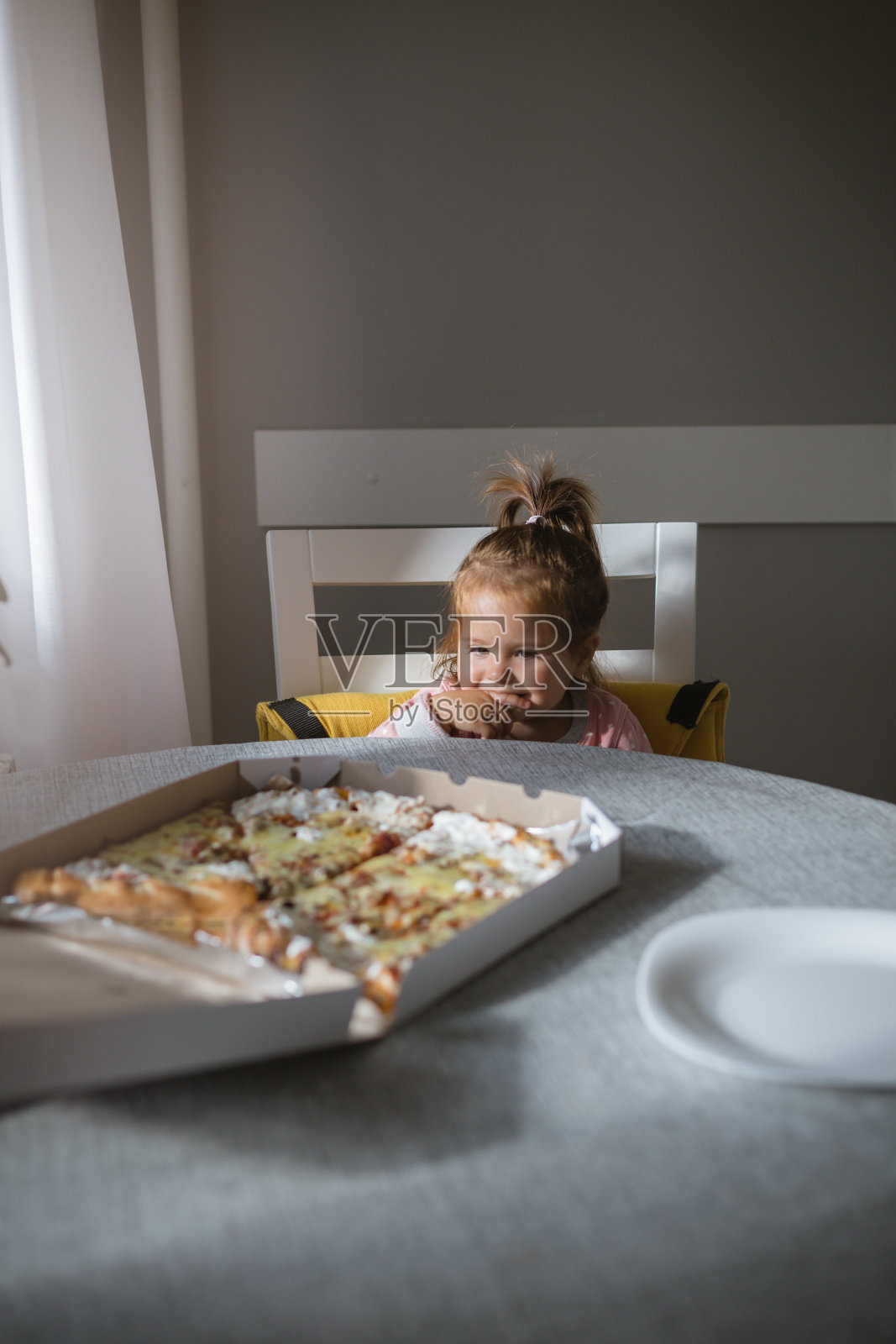 桌上放着一个小女孩的披萨照片摄影图片