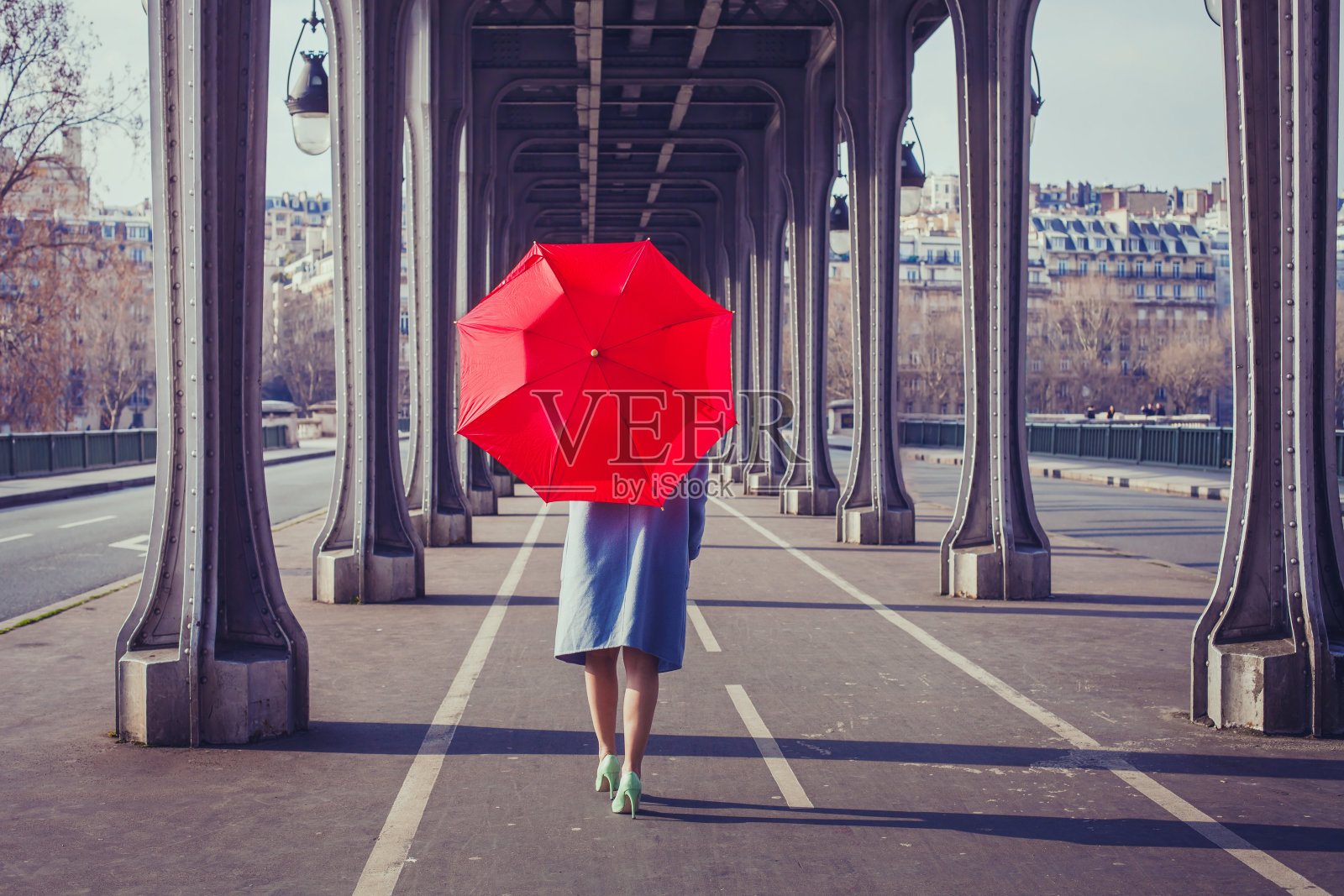 拿着红伞走在巴黎街道上的女人照片摄影图片