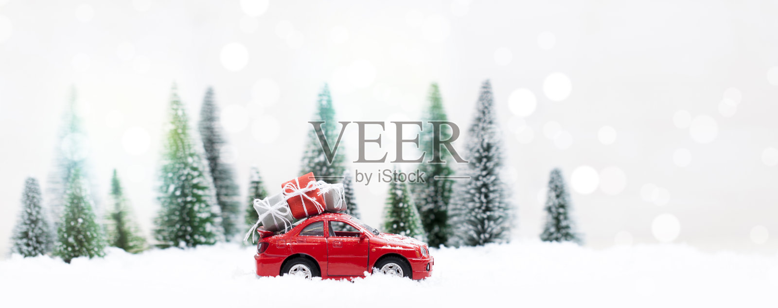 白雪覆盖的冬日森林，红色的汽车载着圣诞礼物照片摄影图片