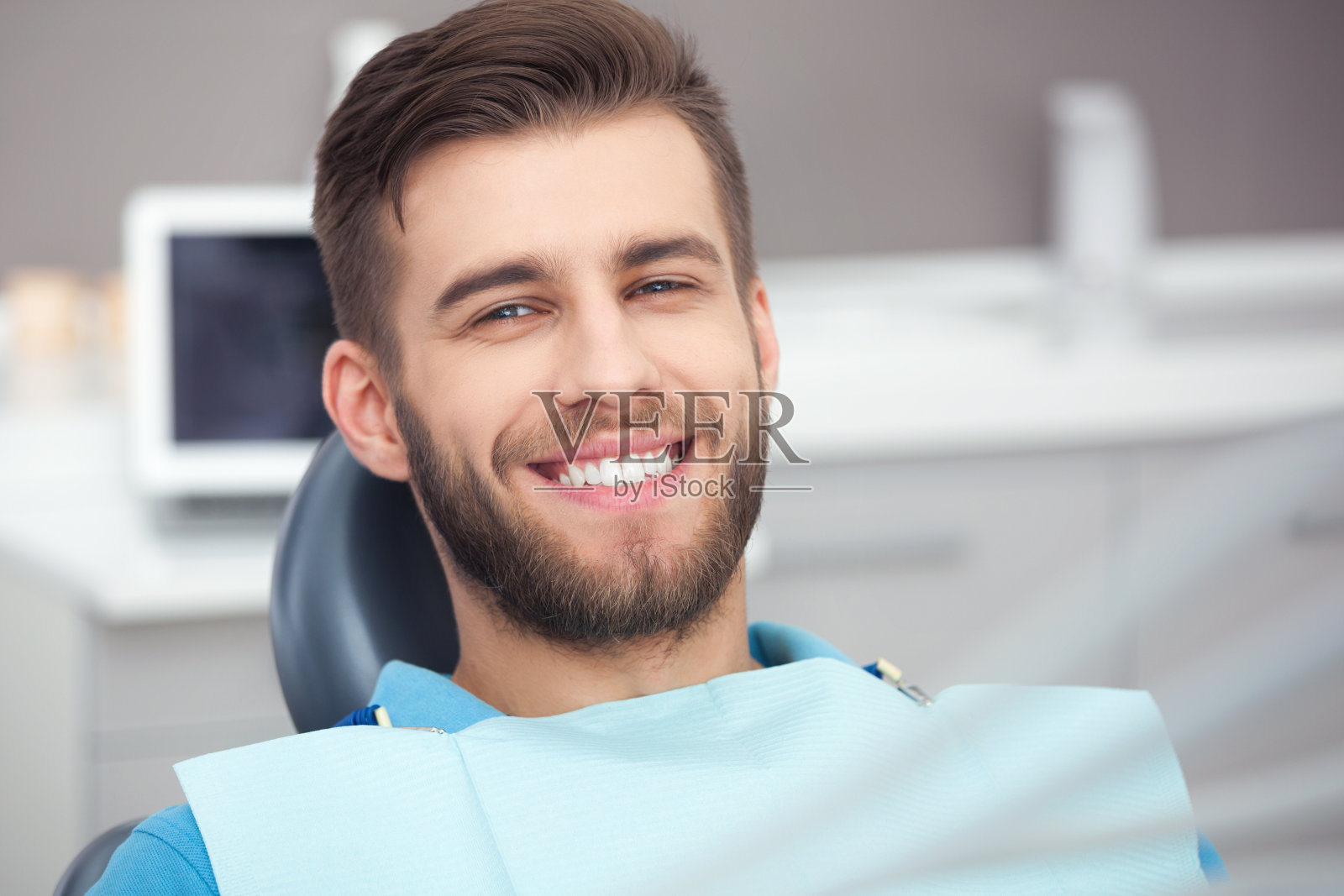 快乐的病人在牙科椅的肖像。照片摄影图片