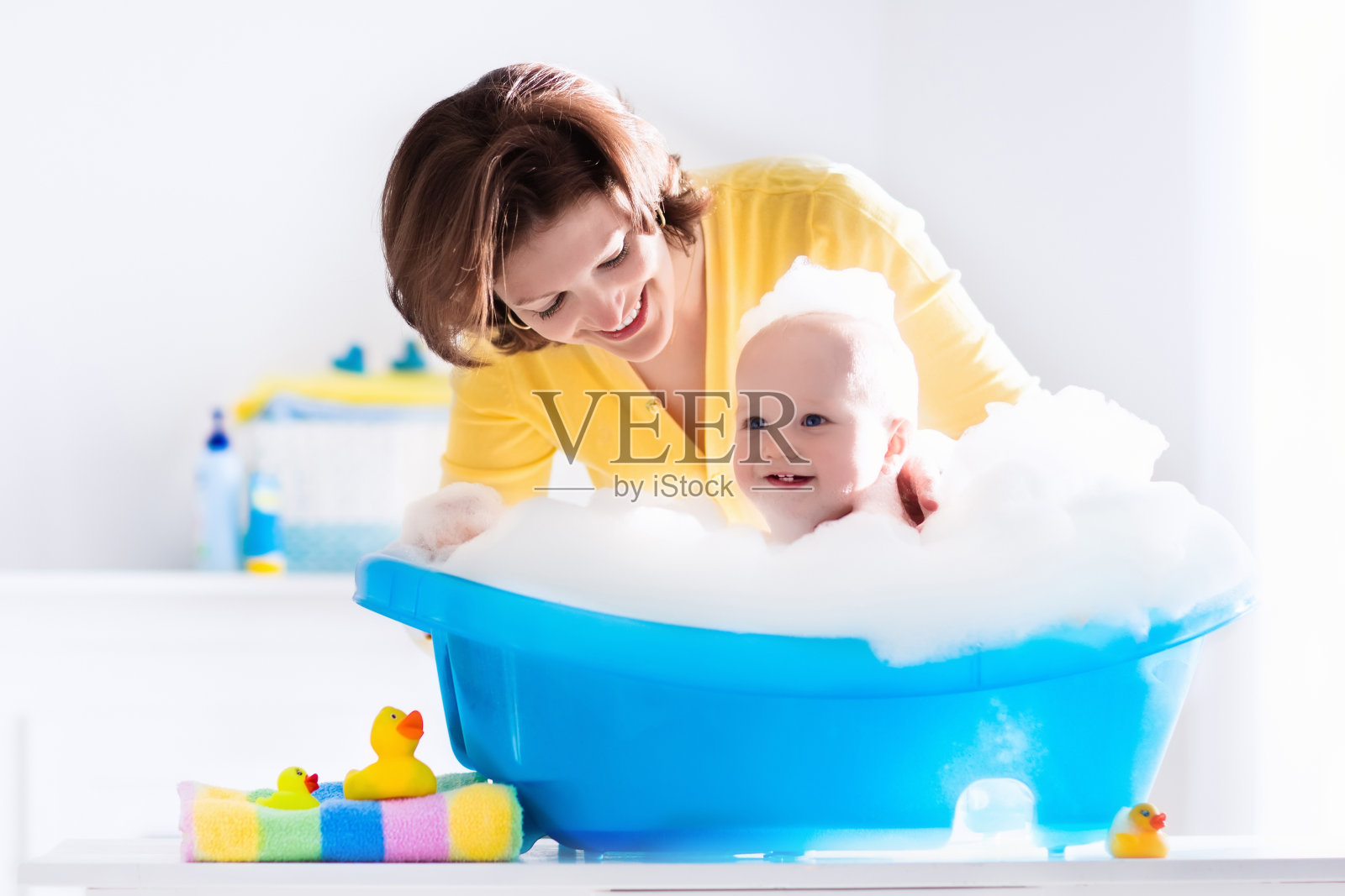 快乐的年轻妈妈正在给男婴洗澡照片摄影图片