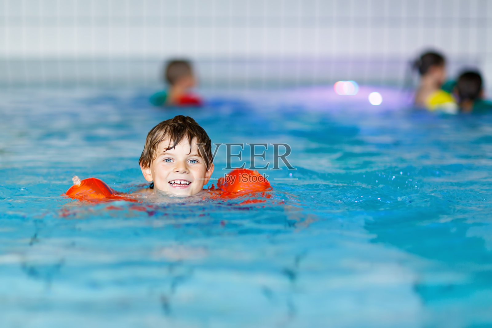 游泳的小男孩在室内游泳池学习游泳照片摄影图片