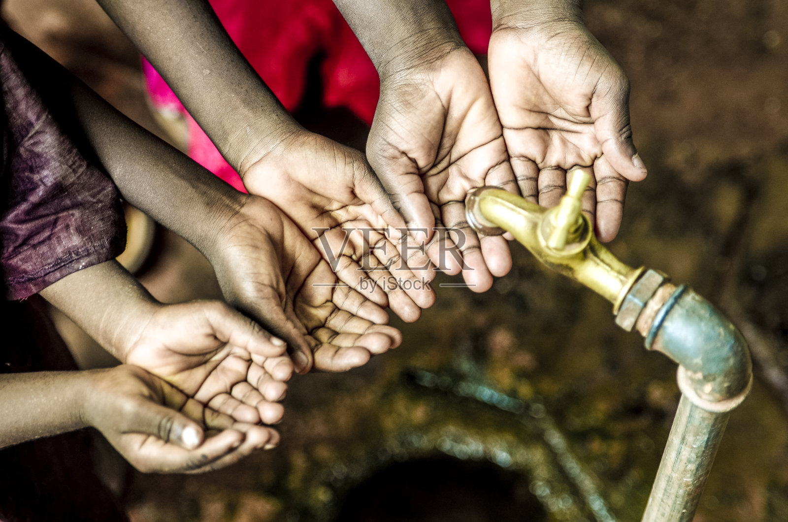 三个非洲儿童手握水龙头下的杯子照片摄影图片