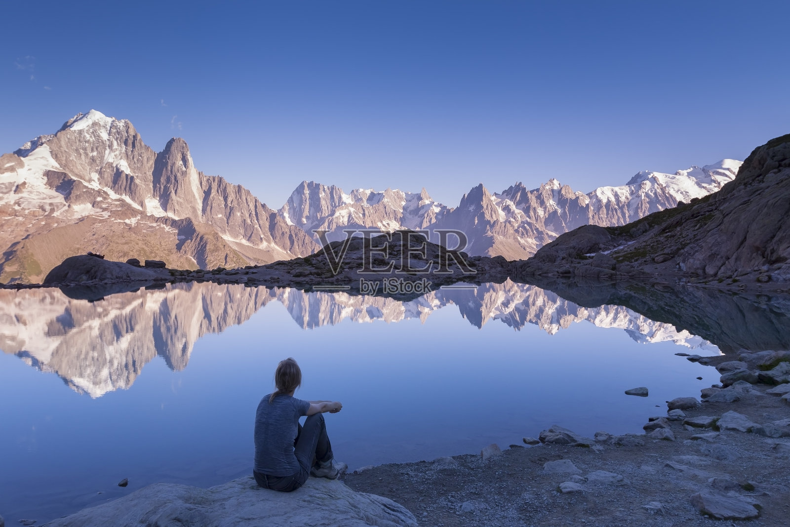 女人看着阿尔卑斯山脉和美丽的倒影在湖中照片摄影图片