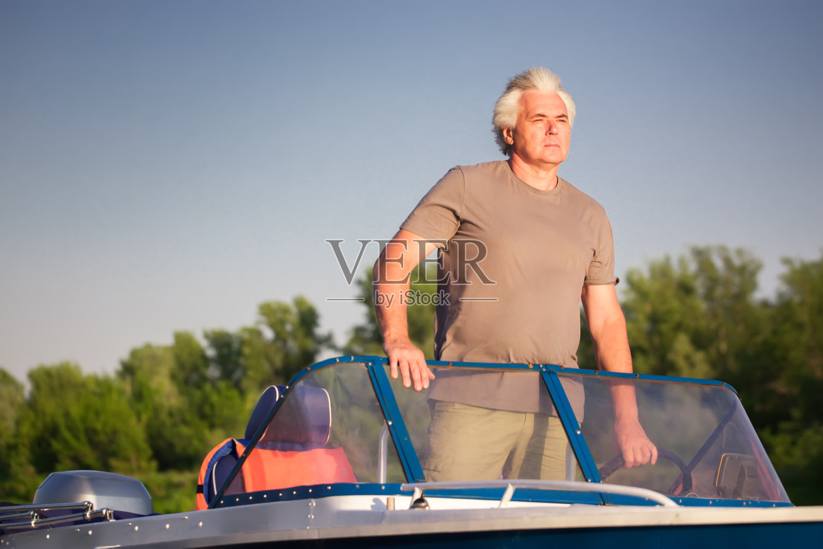 成熟的男人驾驶摩托艇。照片摄影图片
