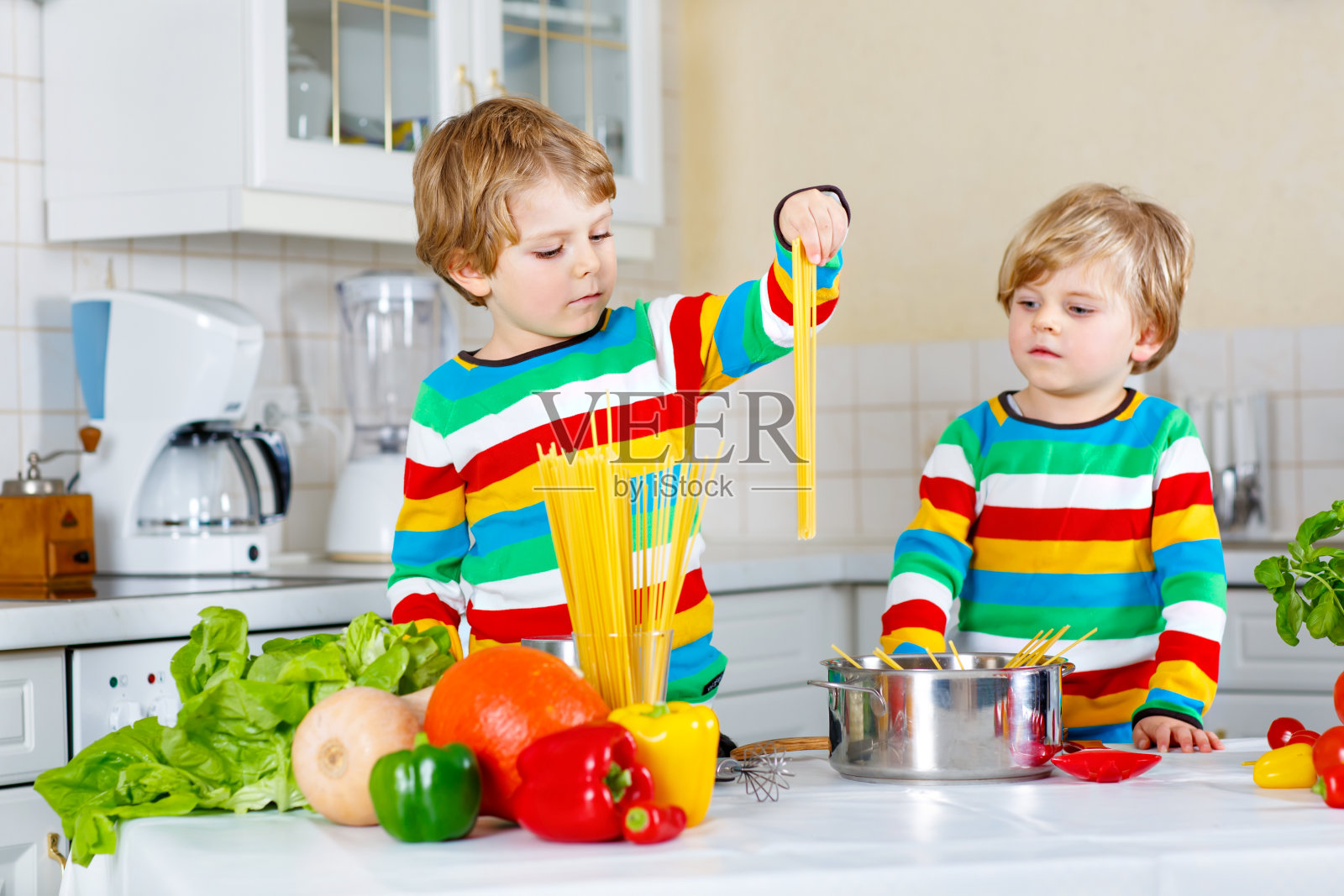 两个小男孩用蔬菜做意大利面照片摄影图片