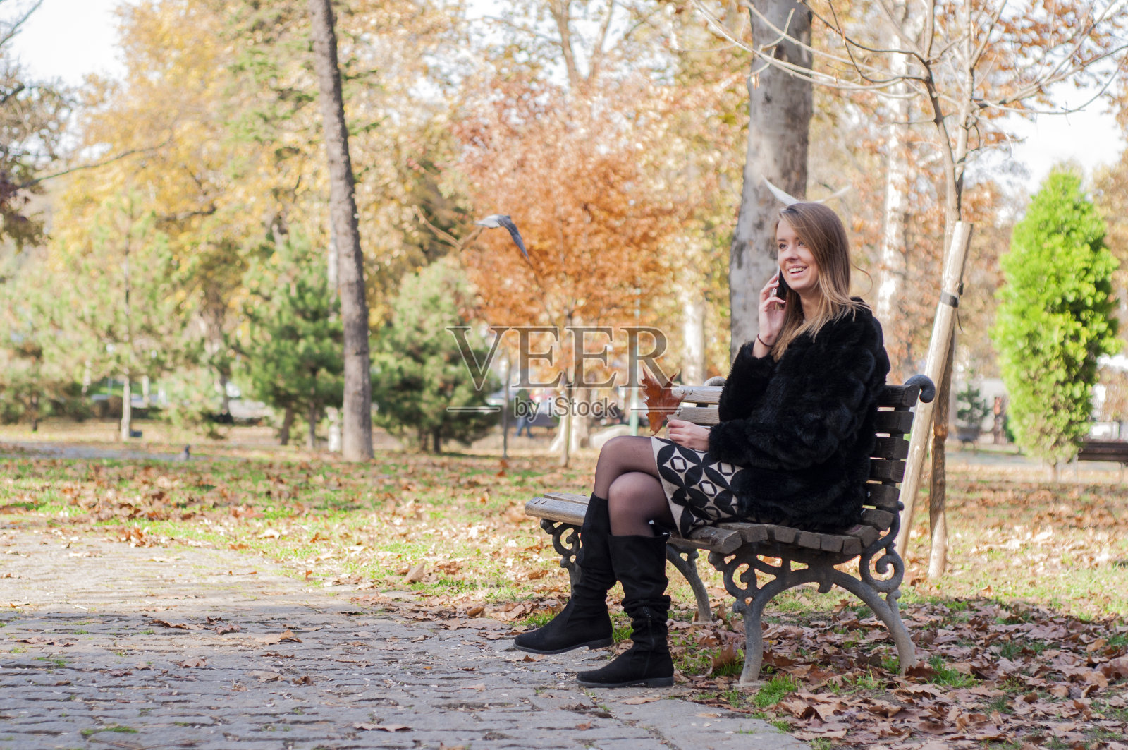 一个孤独的女人坐在城市公园的长椅上。照片摄影图片