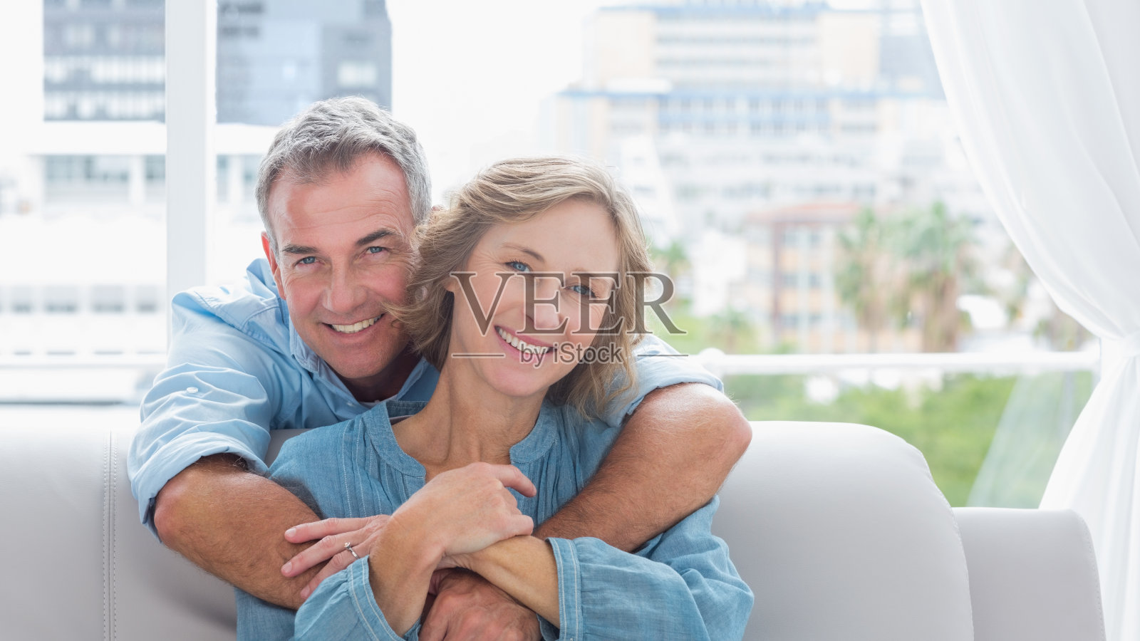 心满意足的男人在沙发上拥抱他的妻子照片摄影图片
