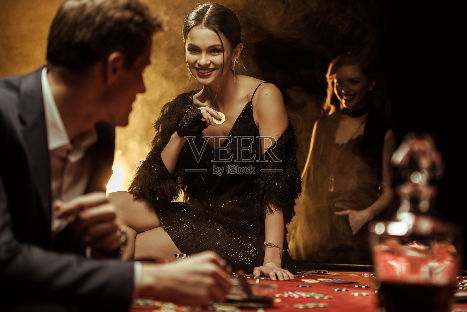 一个笑容灿烂的女人坐在赌桌上拿着赌场筹码照片摄影图片