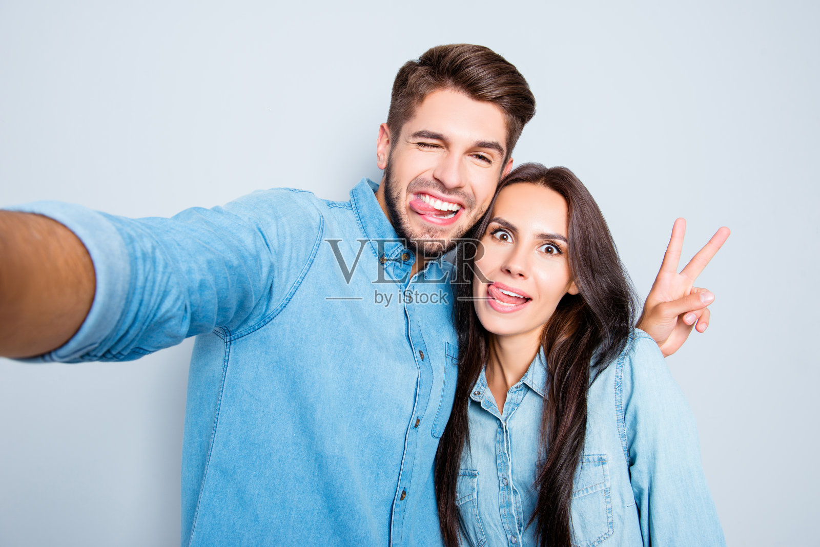 一对搞笑的情侣在自拍时展示舌头和手势照片摄影图片