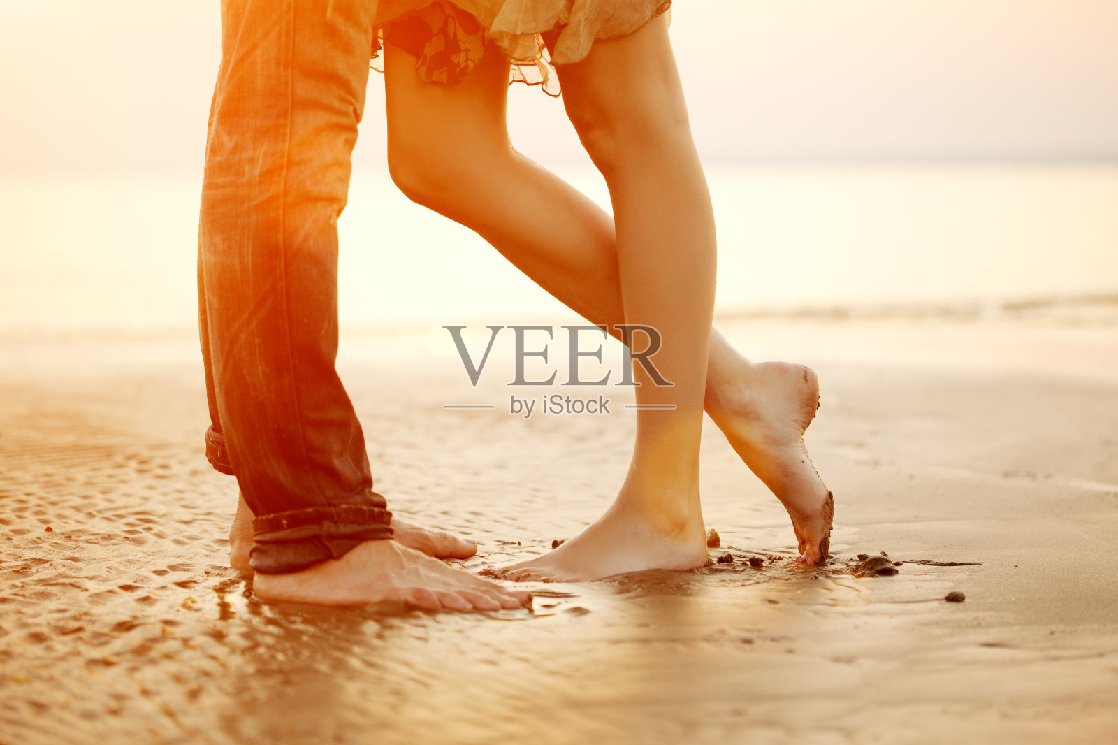 相爱的年轻情侣在日落的海滩上拥抱、亲吻照片摄影图片