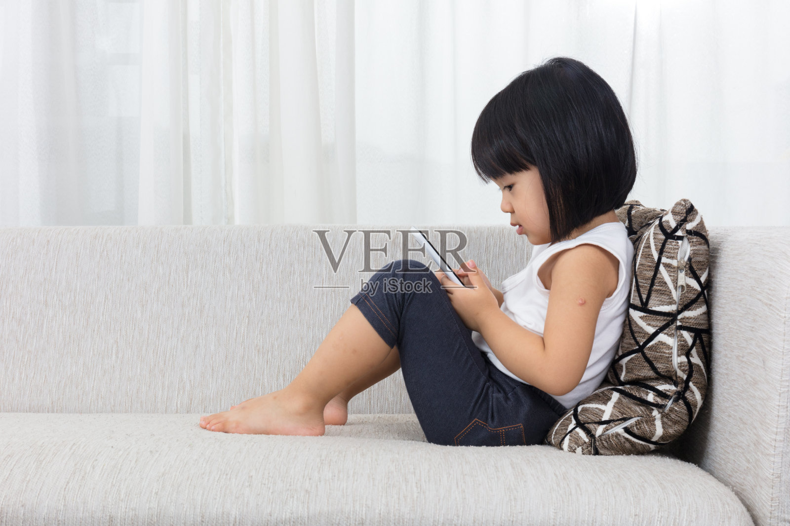 亚洲华人小女孩躺在沙发上玩手机照片摄影图片