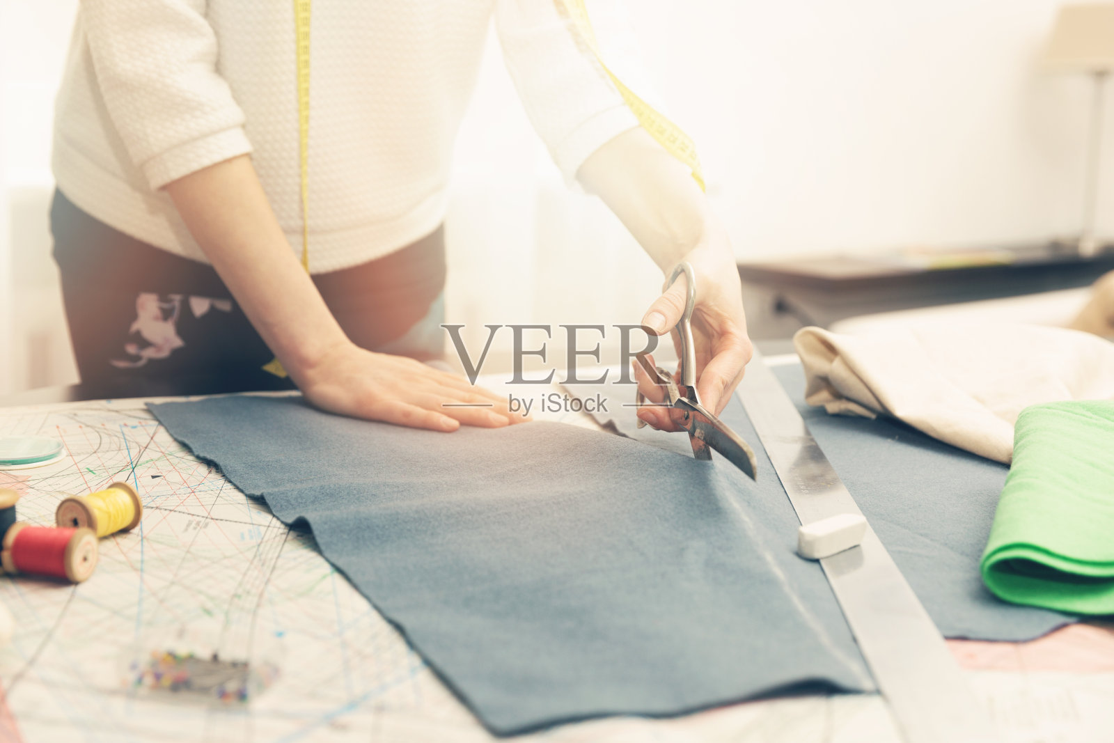 裁缝车间-女裁缝用剪刀裁剪布料照片摄影图片