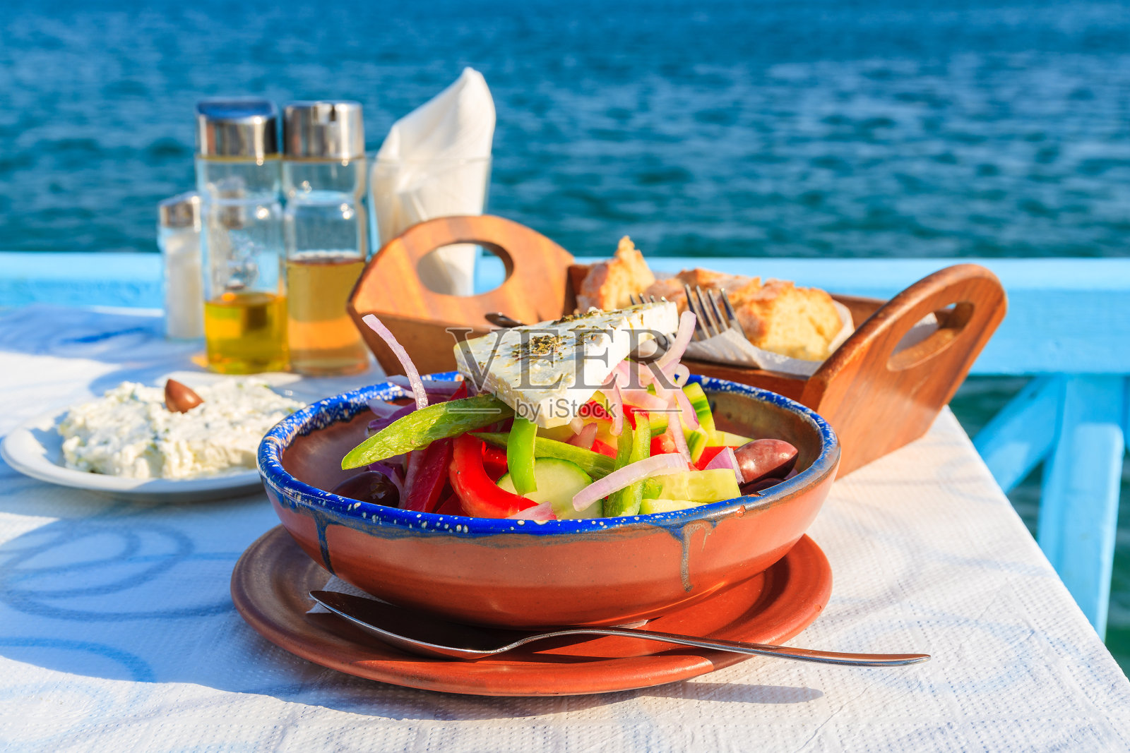 希腊萨摩斯岛，蓝色海水背景下的希腊酒馆桌上的希腊沙拉照片摄影图片