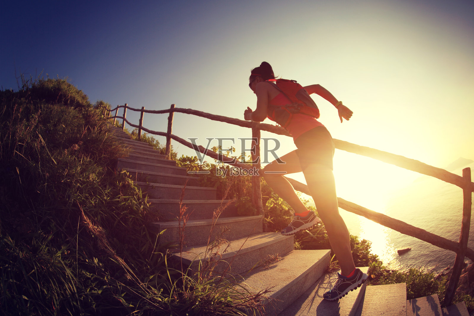 健身女跑步者在海边的山楼梯上跑步，照片摄影图片