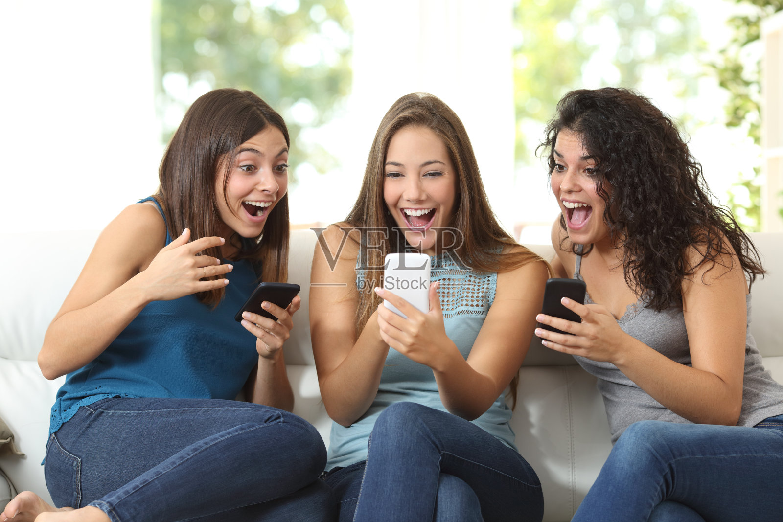 三个朋友惊讶地看着一个智能手机照片摄影图片