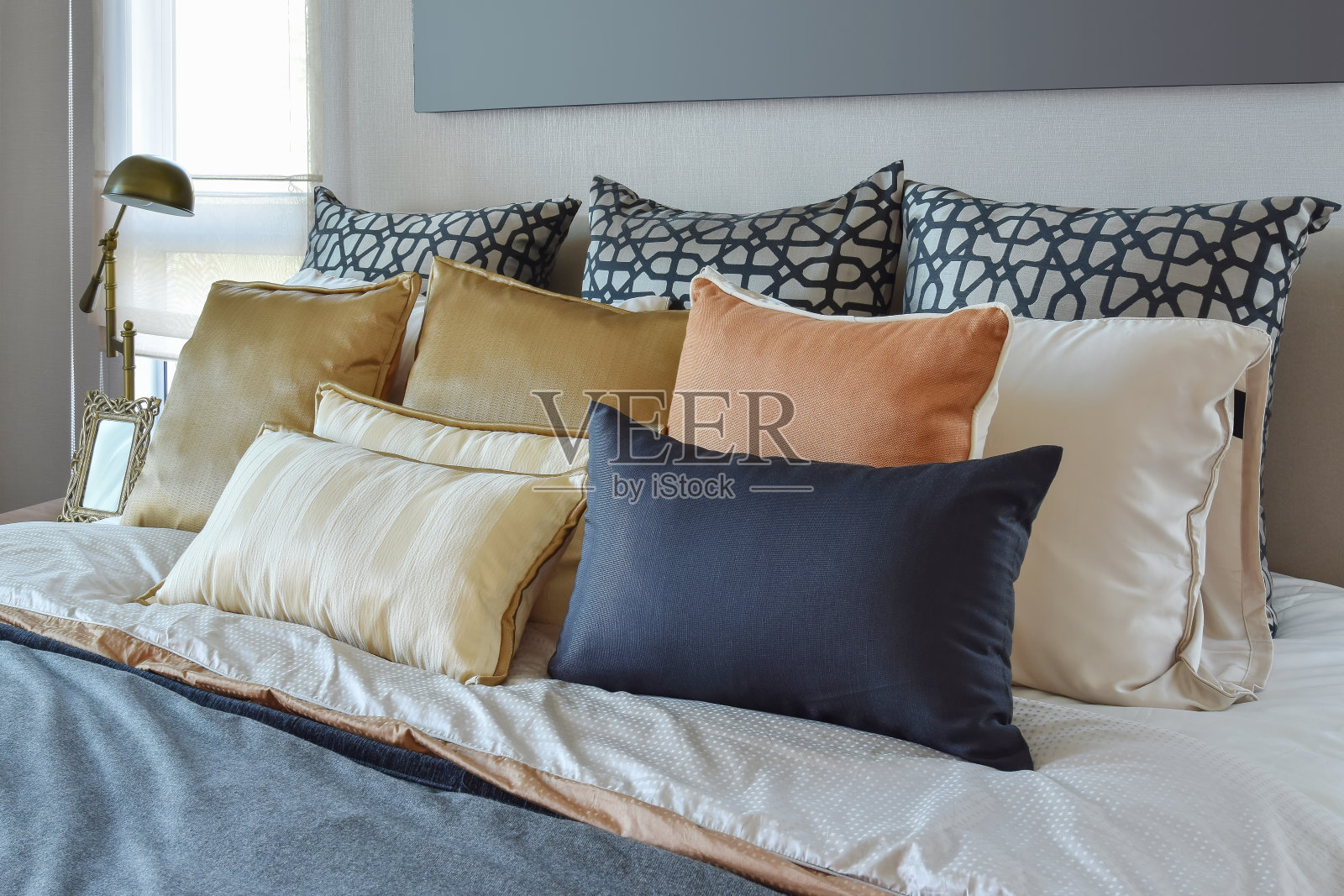 现代的卧室内部，橙色和金色的枕头在床上照片摄影图片