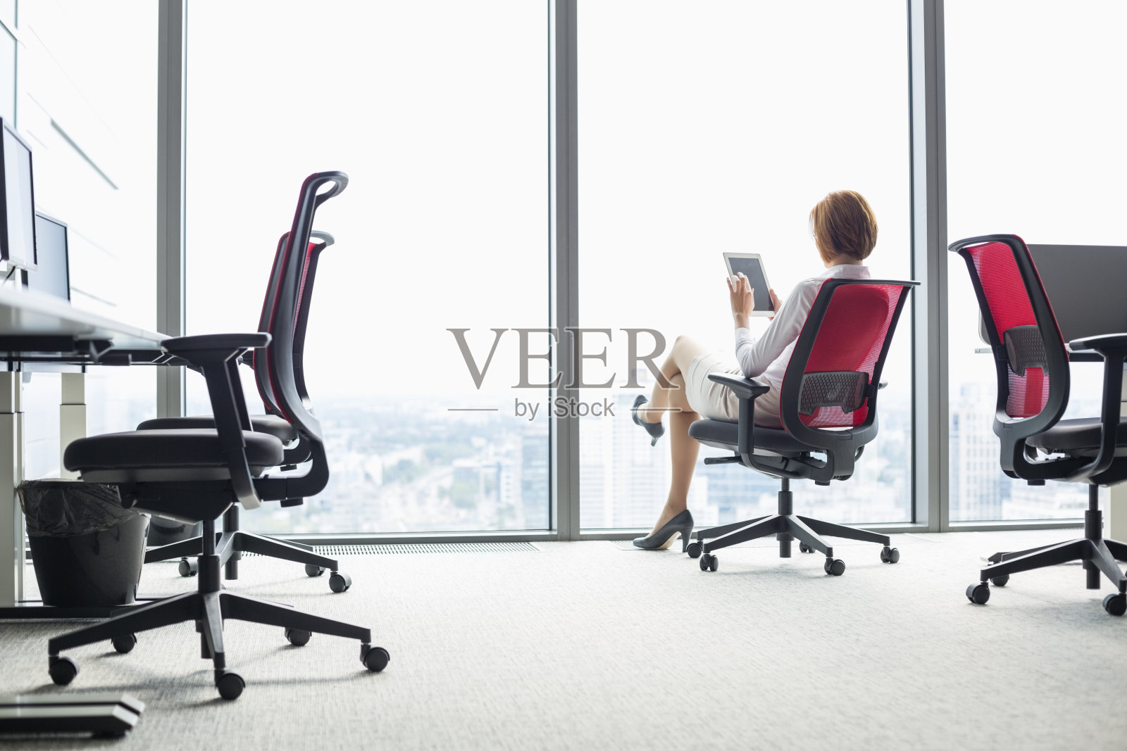 年轻的女商人在办公室的椅子上使用平板电脑照片摄影图片