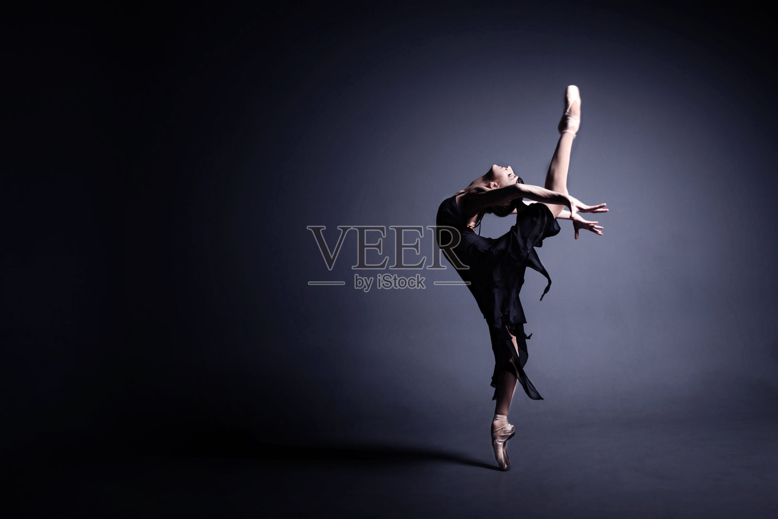 年轻的芭蕾舞女演员穿着黑色的衣服在黑暗中跳舞照片摄影图片