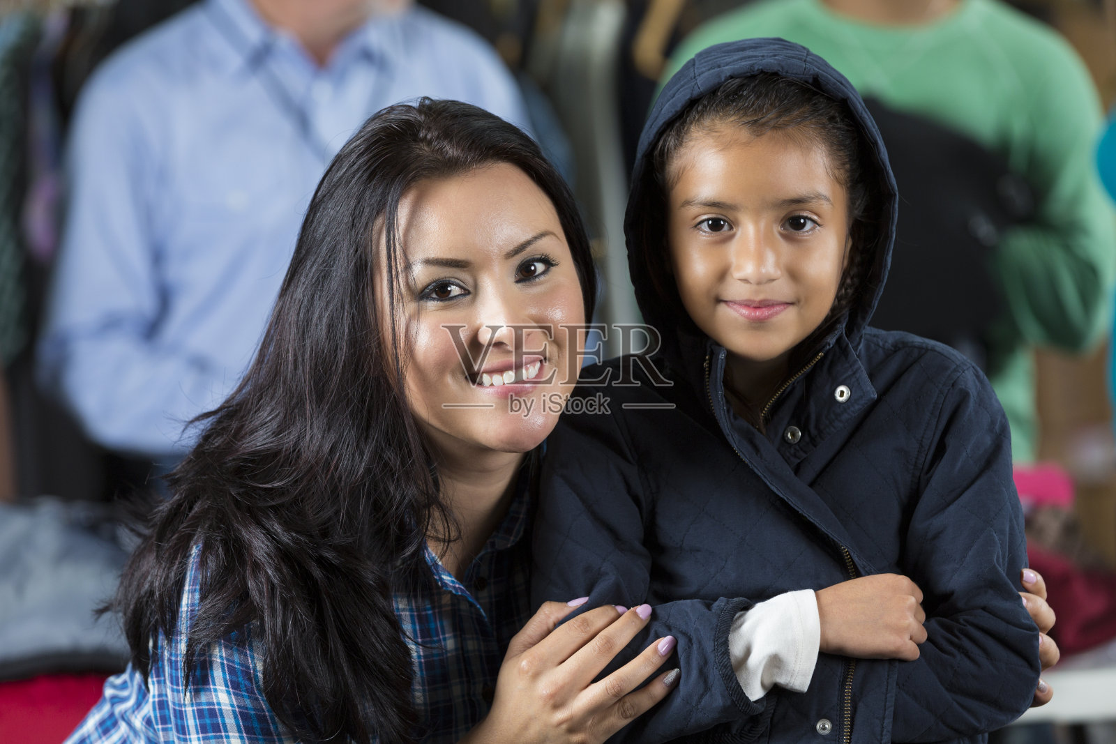 西班牙裔妈妈和女儿在衣帽店接受捐赠照片摄影图片