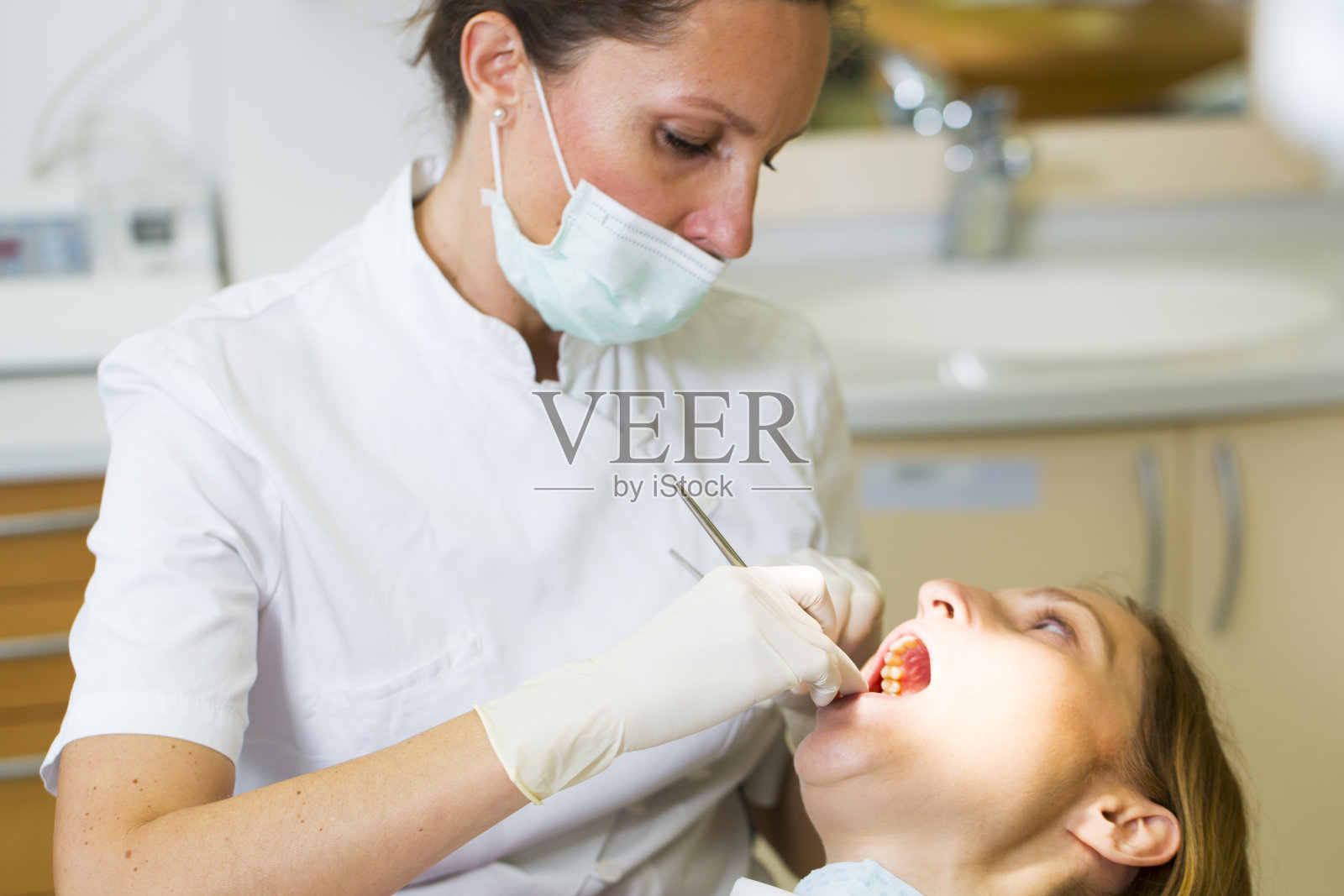 女牙医在牙医椅上与女病人一起工作照片摄影图片