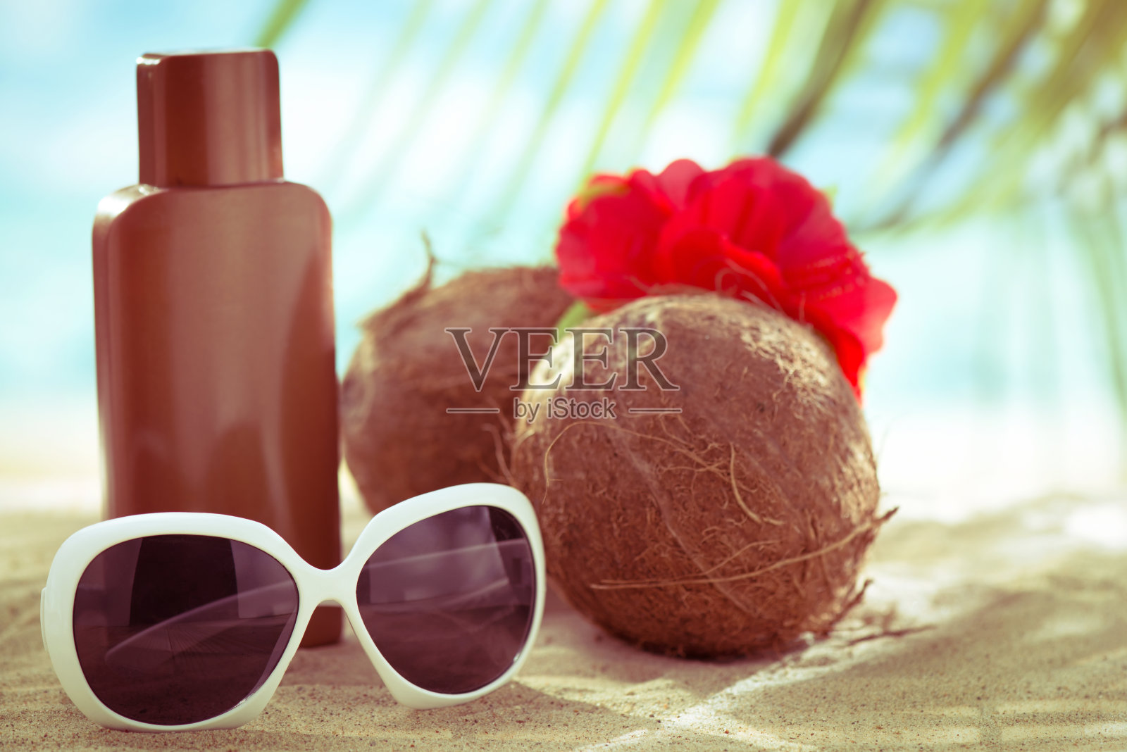 太阳眼镜，防晒霜和椰子在热带海滩上照片摄影图片