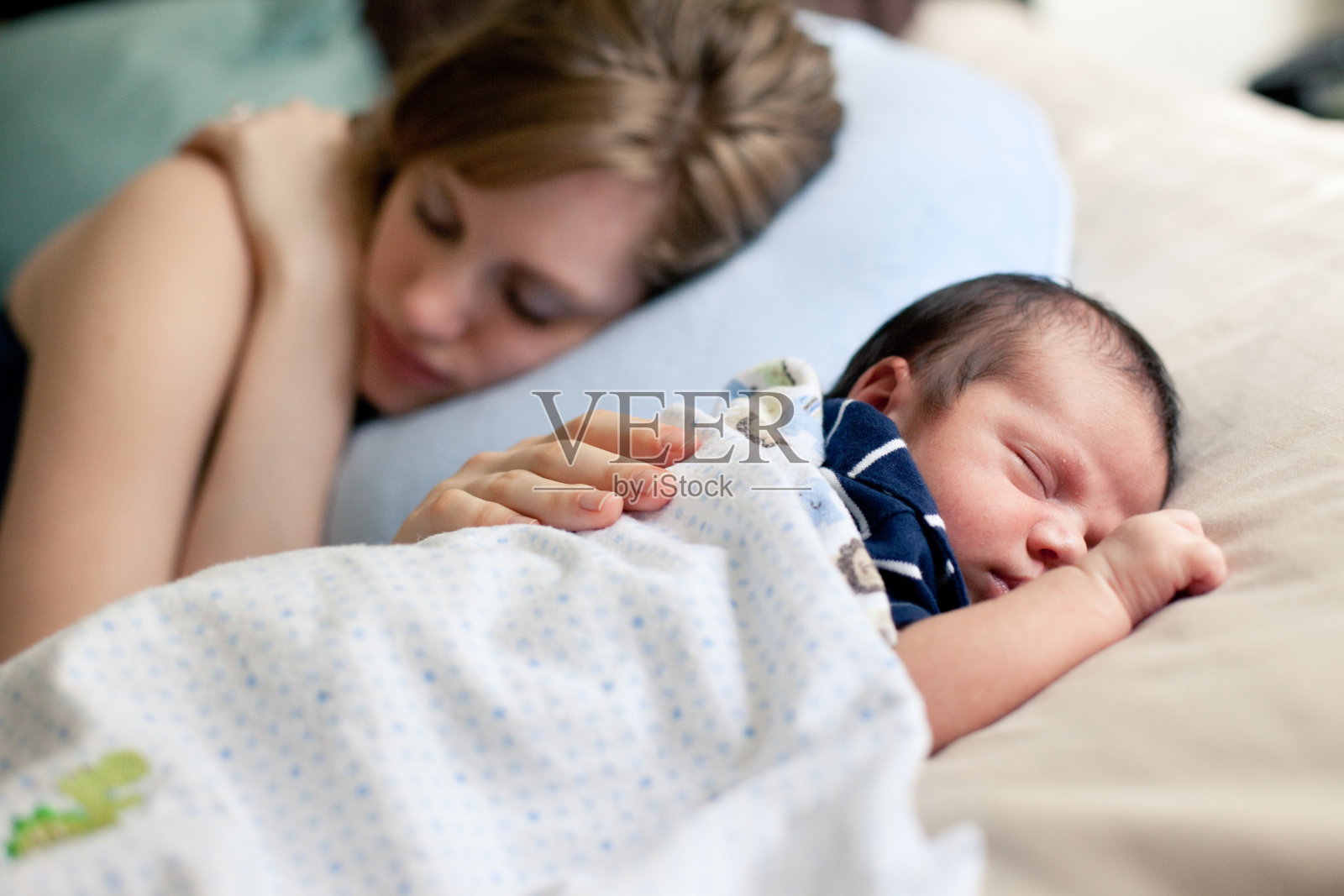 母亲和新生儿一起睡在床上照片摄影图片