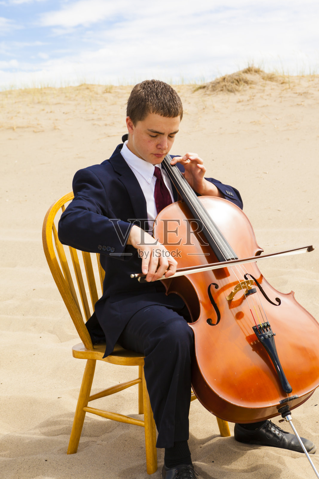 在沙漠中拉大提琴的年轻人照片摄影图片