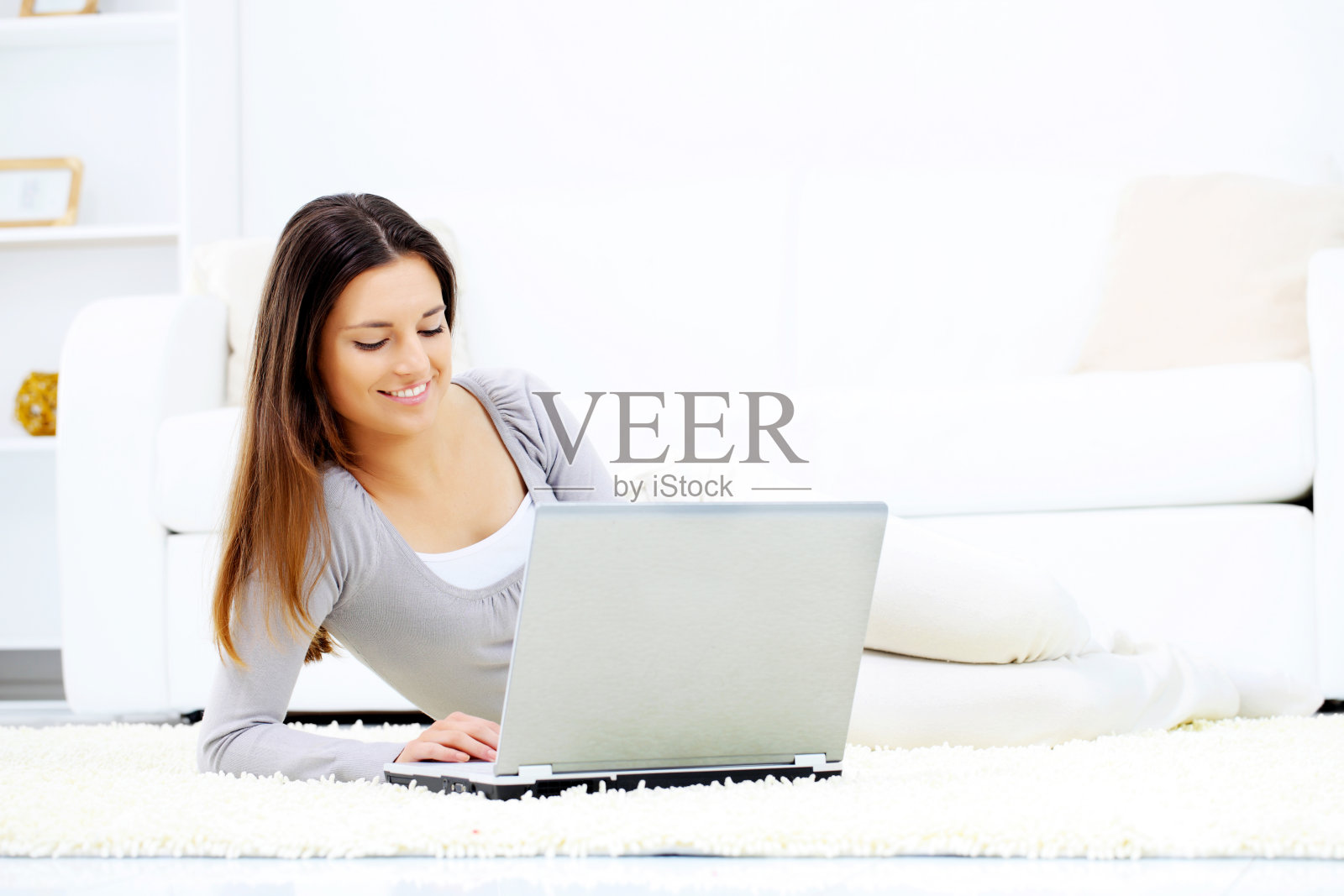年轻的黑发女子在用她的笔记本电脑。照片摄影图片