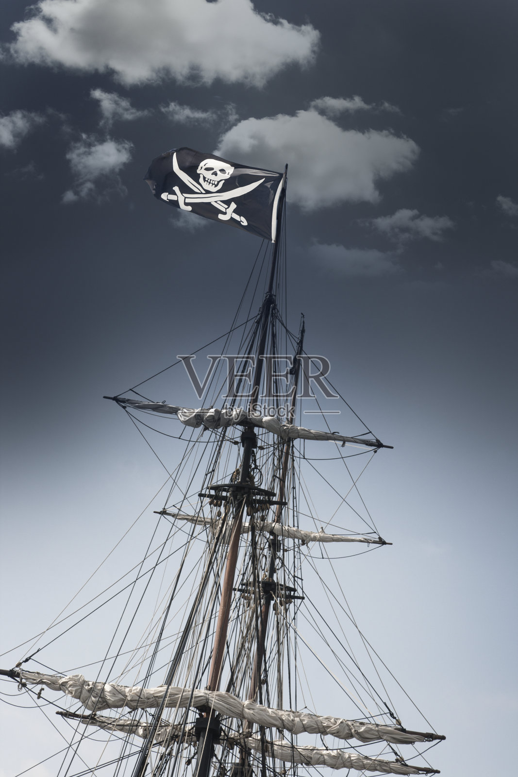 在黑暗的天空下挂着骷髅旗的海盗船照片摄影图片