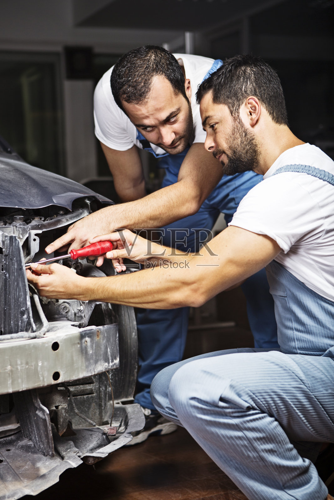年轻的机械师在汽车修理厂修理汽车照片摄影图片