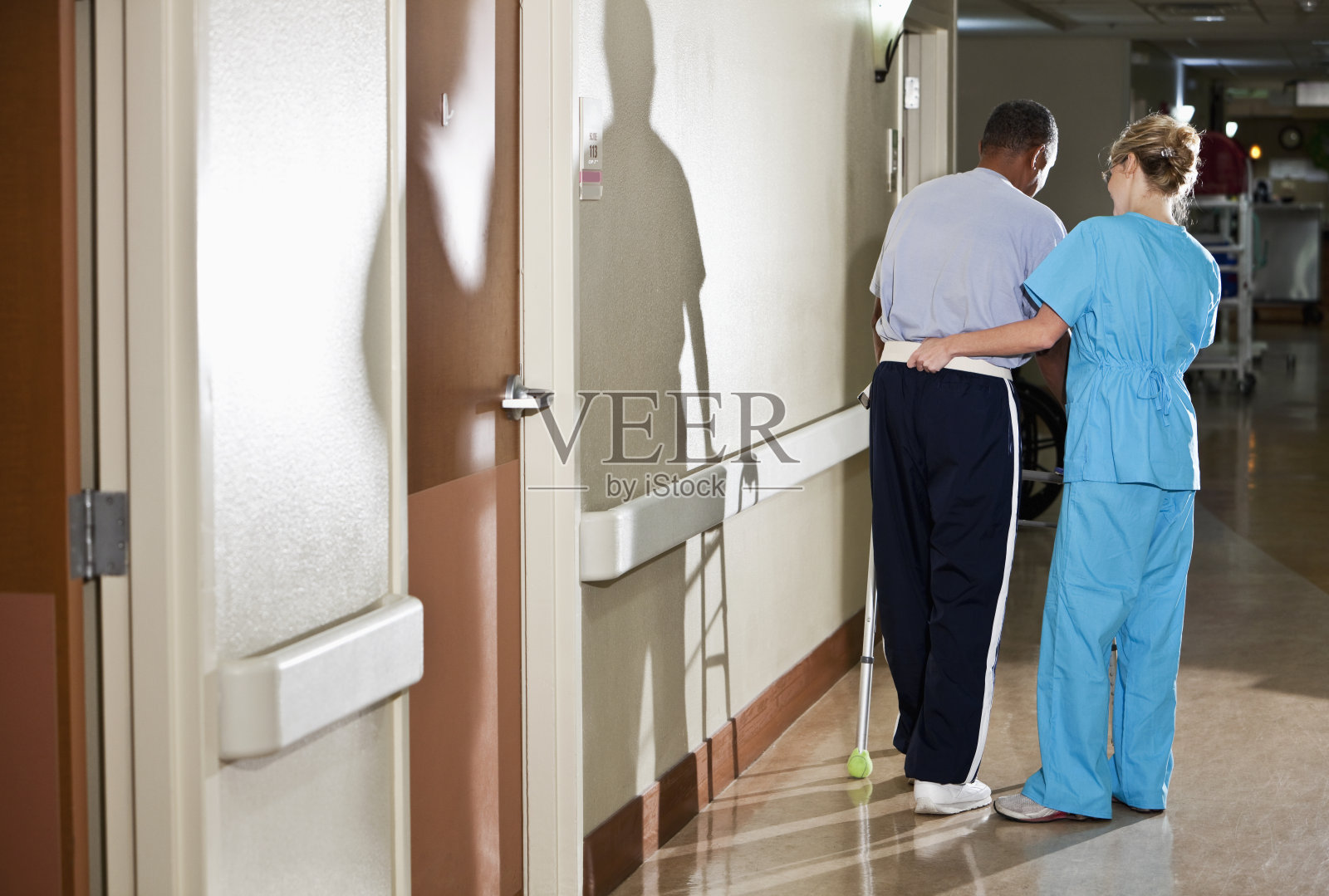 护士帮助病人走过医院走廊照片摄影图片