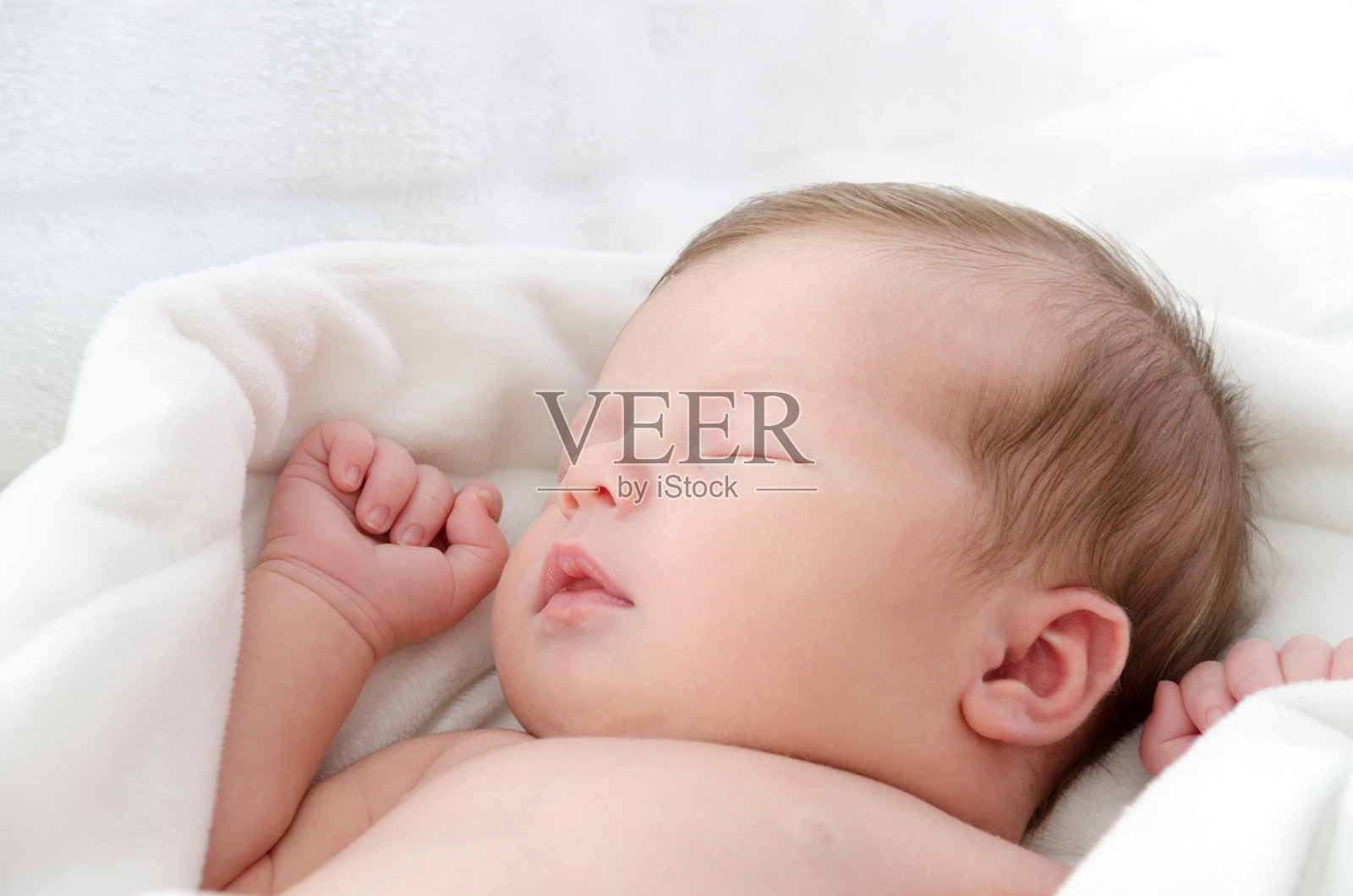 睡在白色毯子里的可爱的婴儿。照片摄影图片