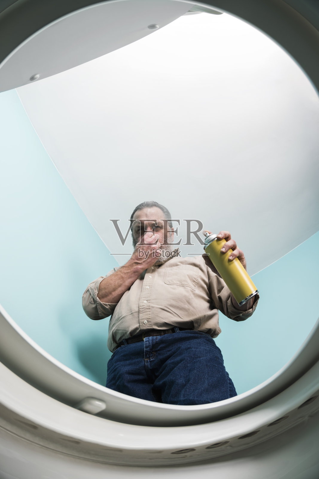 抬头看着一名男子向臭气熏天的厕所喷洒空气清新剂照片摄影图片