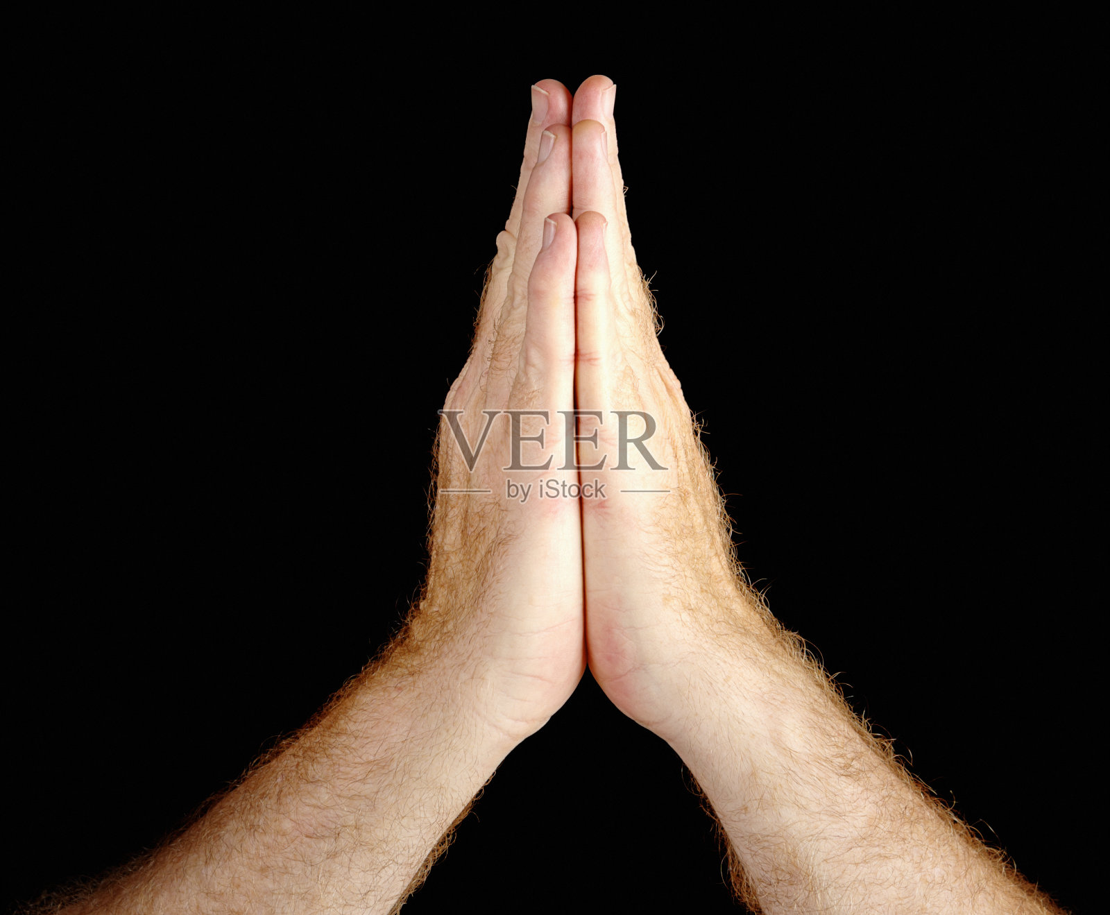 手势:男性双手合十祈祷，背景为黑色照片摄影图片