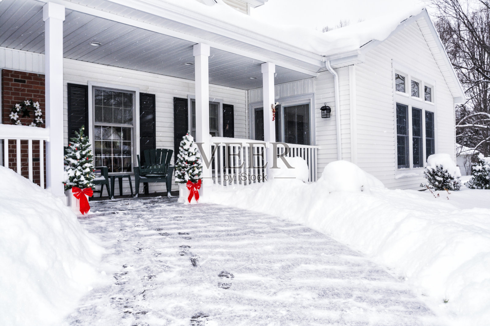 房子前面人行道上的冬雪脚印照片摄影图片