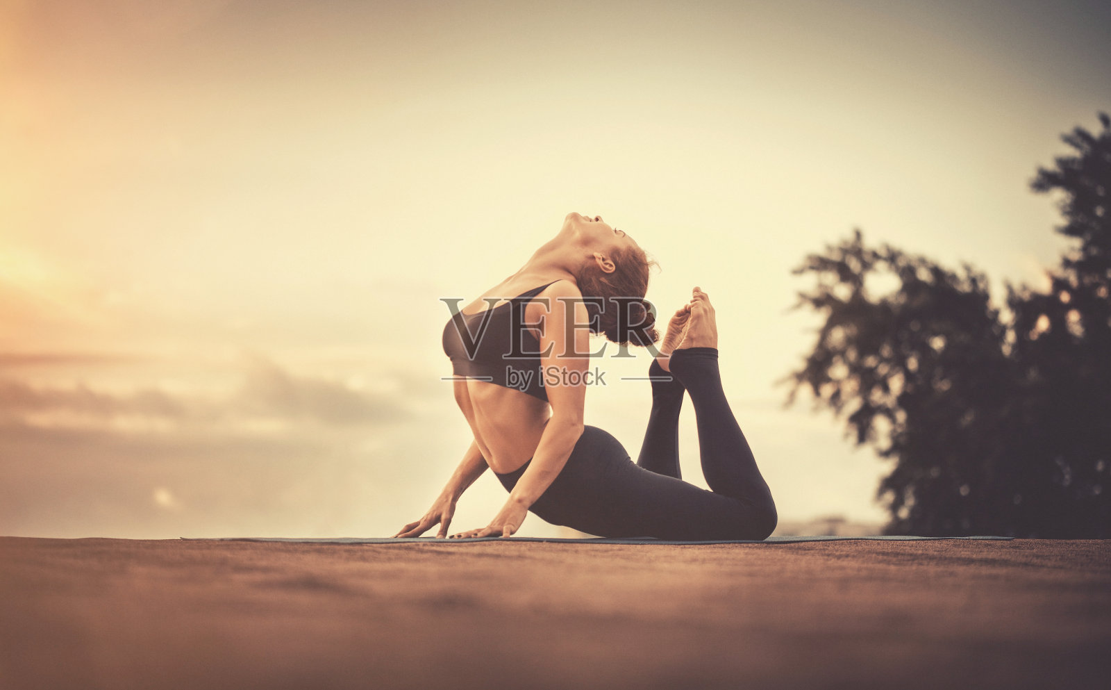 年轻女子在日落时做瑜伽练习照片摄影图片